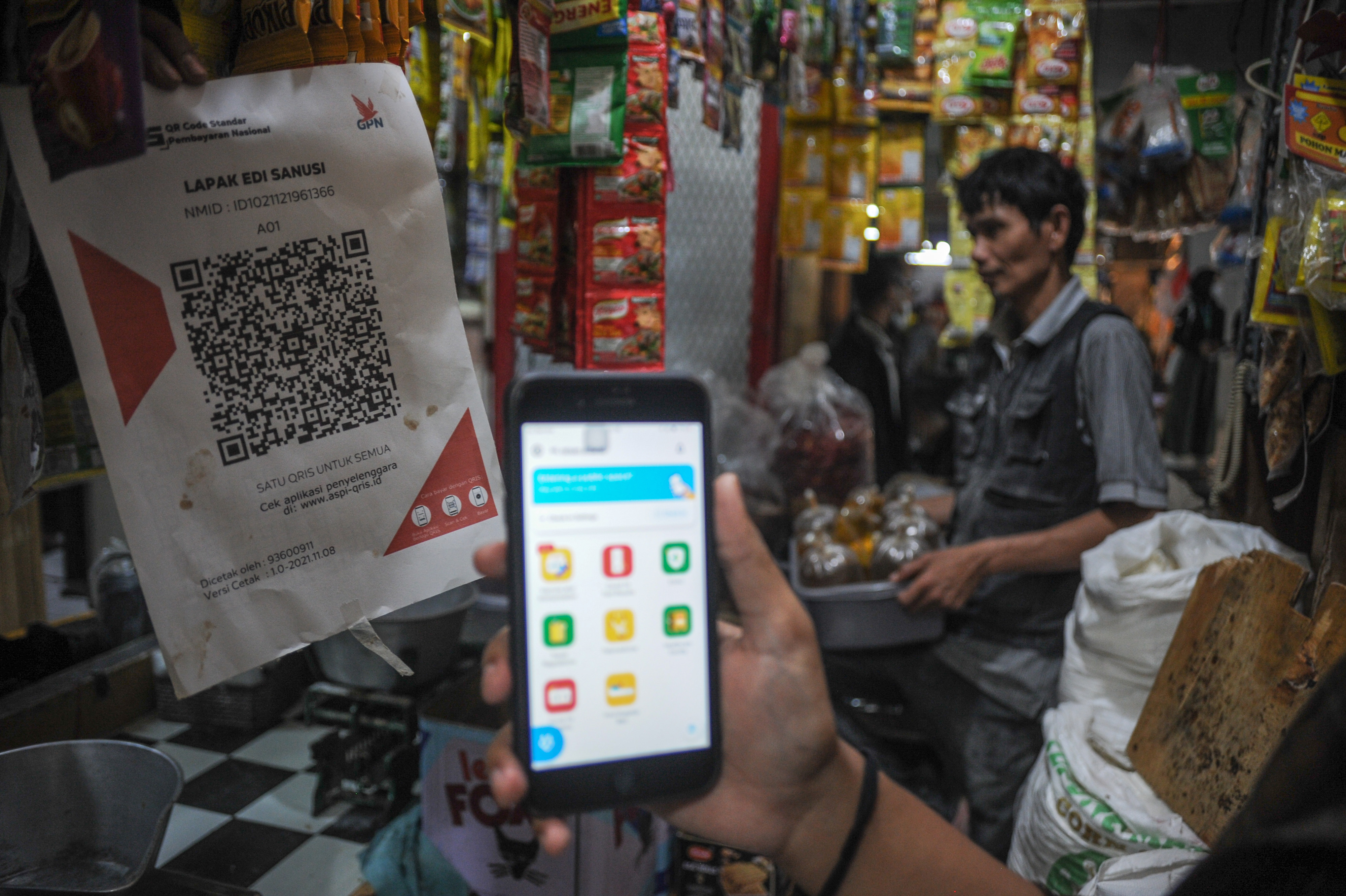 Warga menunjukkan aplikasi PeduliLindungi saat membeli minyak goreng curah di pasar.