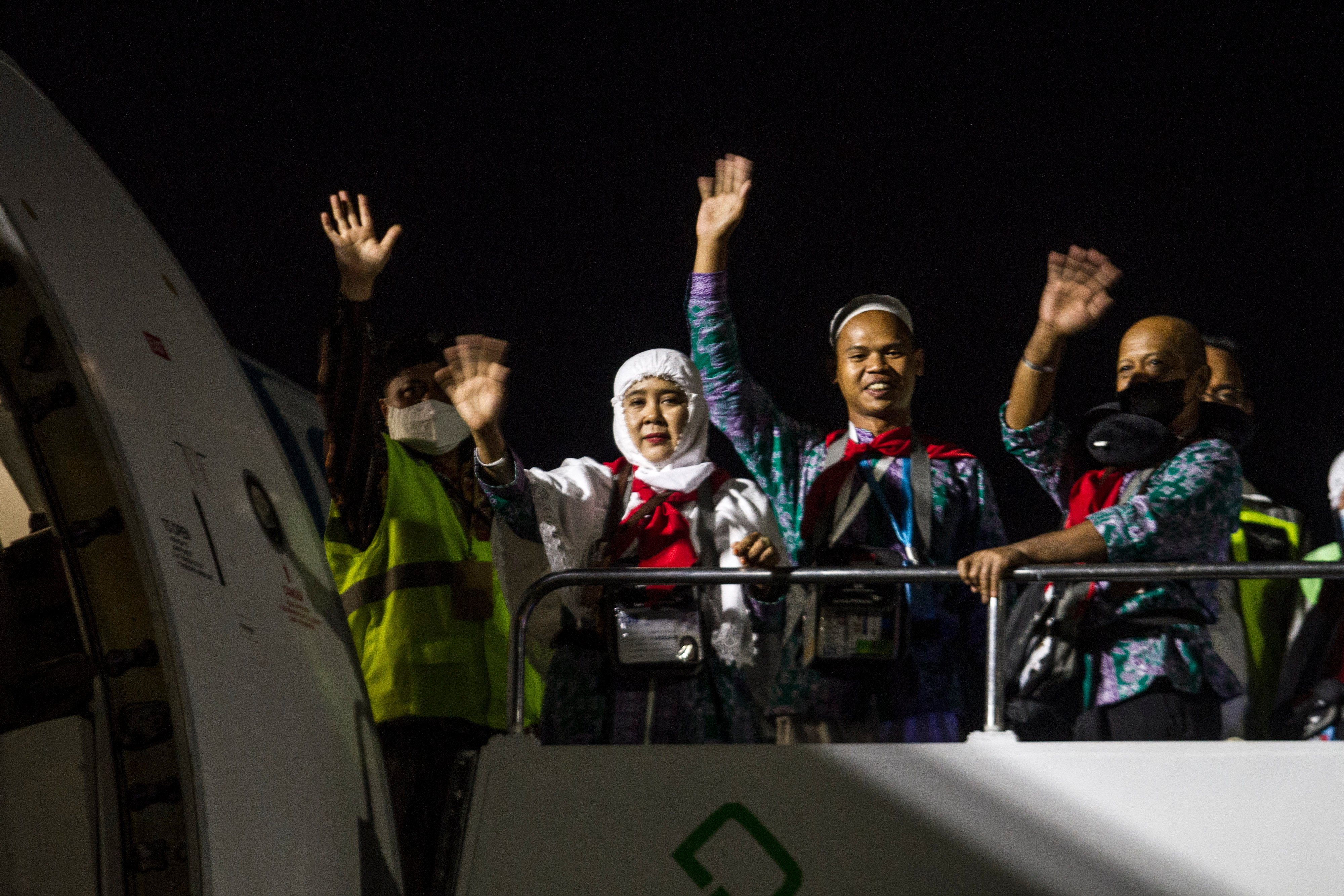 Jamaah calon haji melambaikan tangan saat menaiki tangga menuju pesawat.