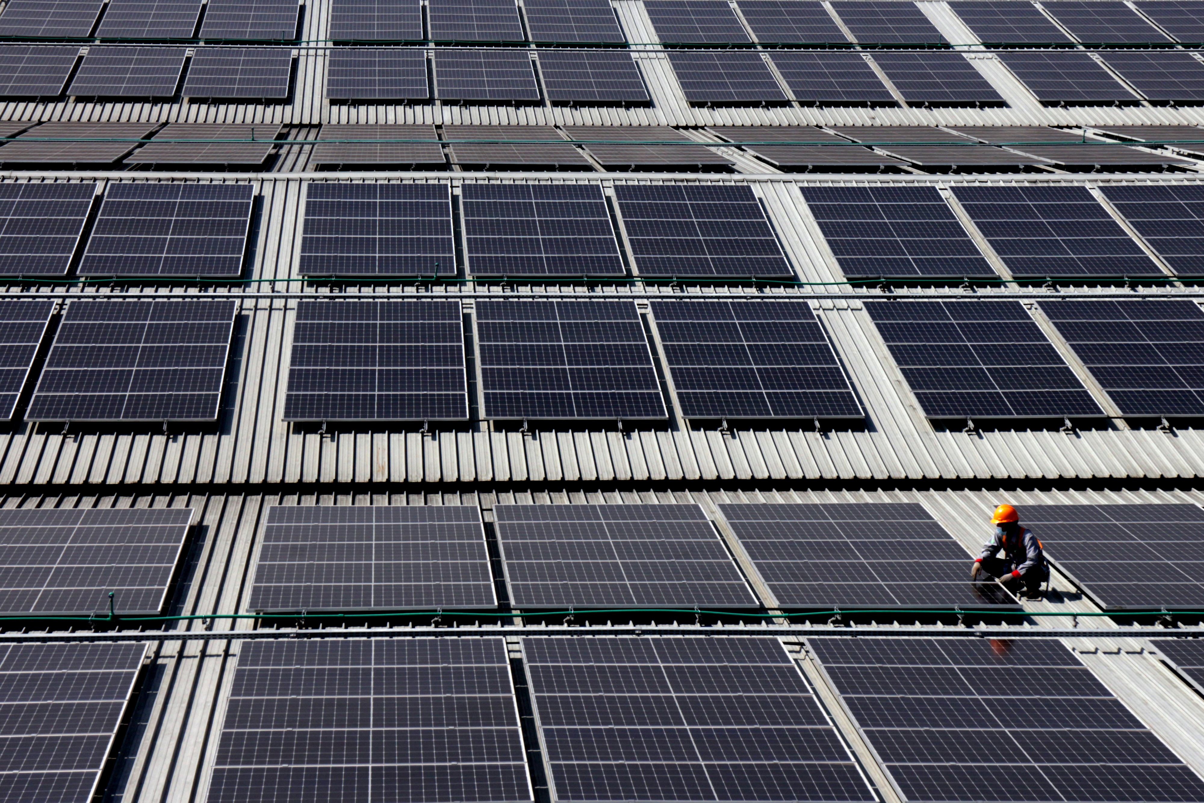 Pekerja melakukan perawatan rutin di pembangkit listrik tenaga surya (PLTS).