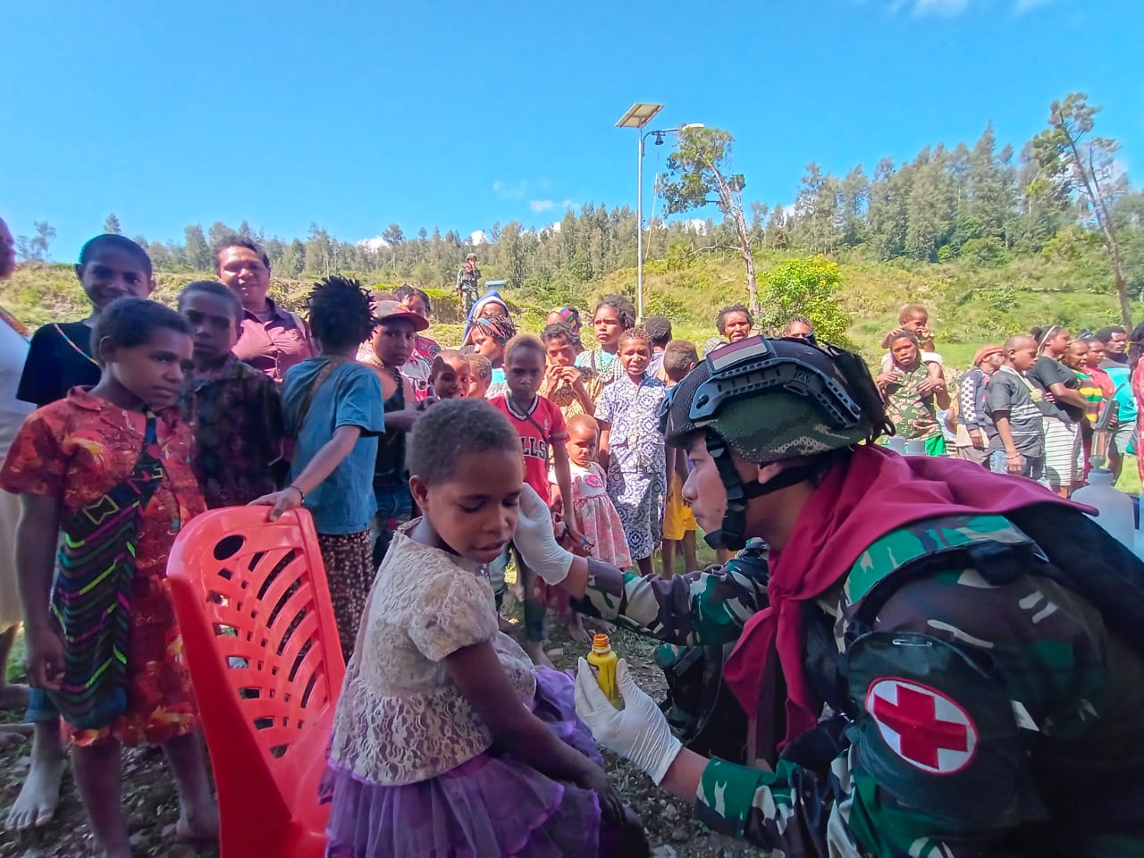 Seorang prajurit Satgas Kodim Yonif Para Raider 328/Dirgahayu tengah mengobati anak Papua.