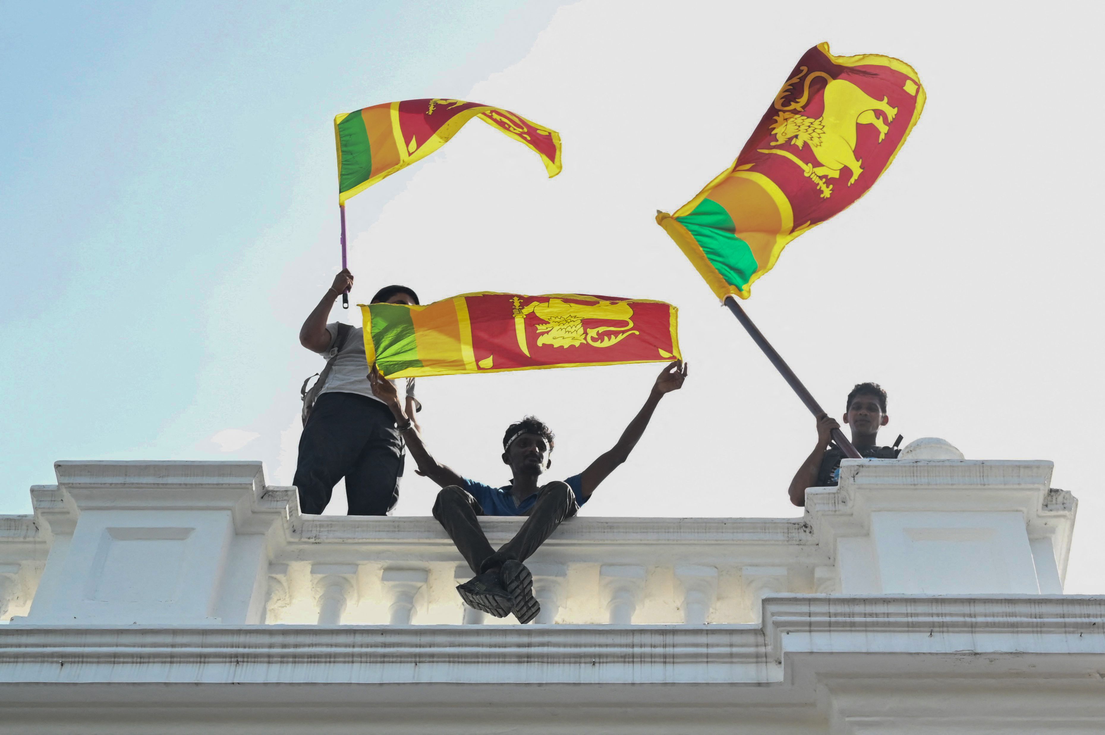 Rakyat Sri Lanka mengibarkan bendera dari atas balkon kantor Perdana Menteri.