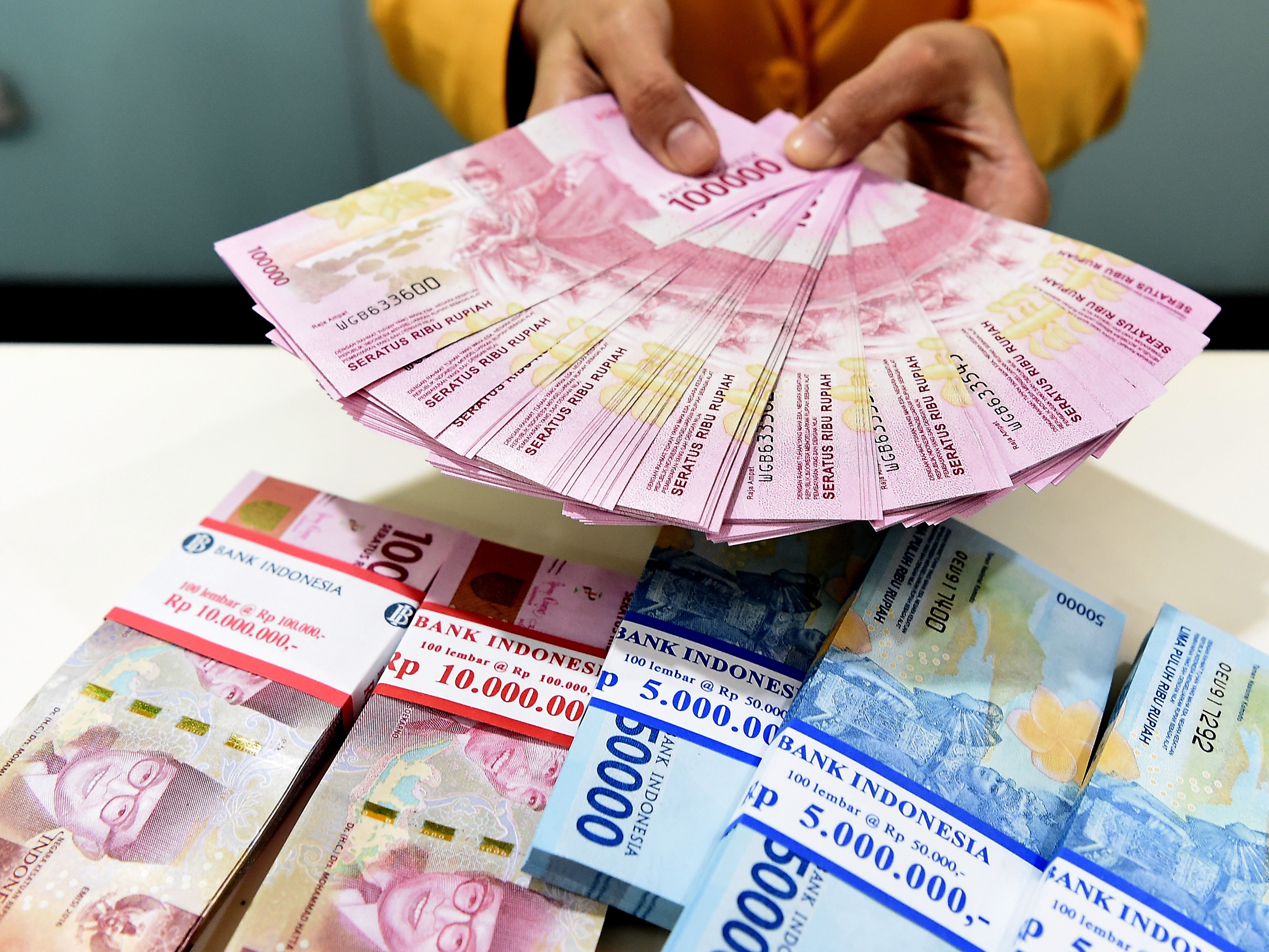 Seorang teller Bank Mandiri menunjukkan uang pecahan Rp100.000 dan Rp50.000 di Plasa Mandiri, Jakarta, beberapa waktu lalu.