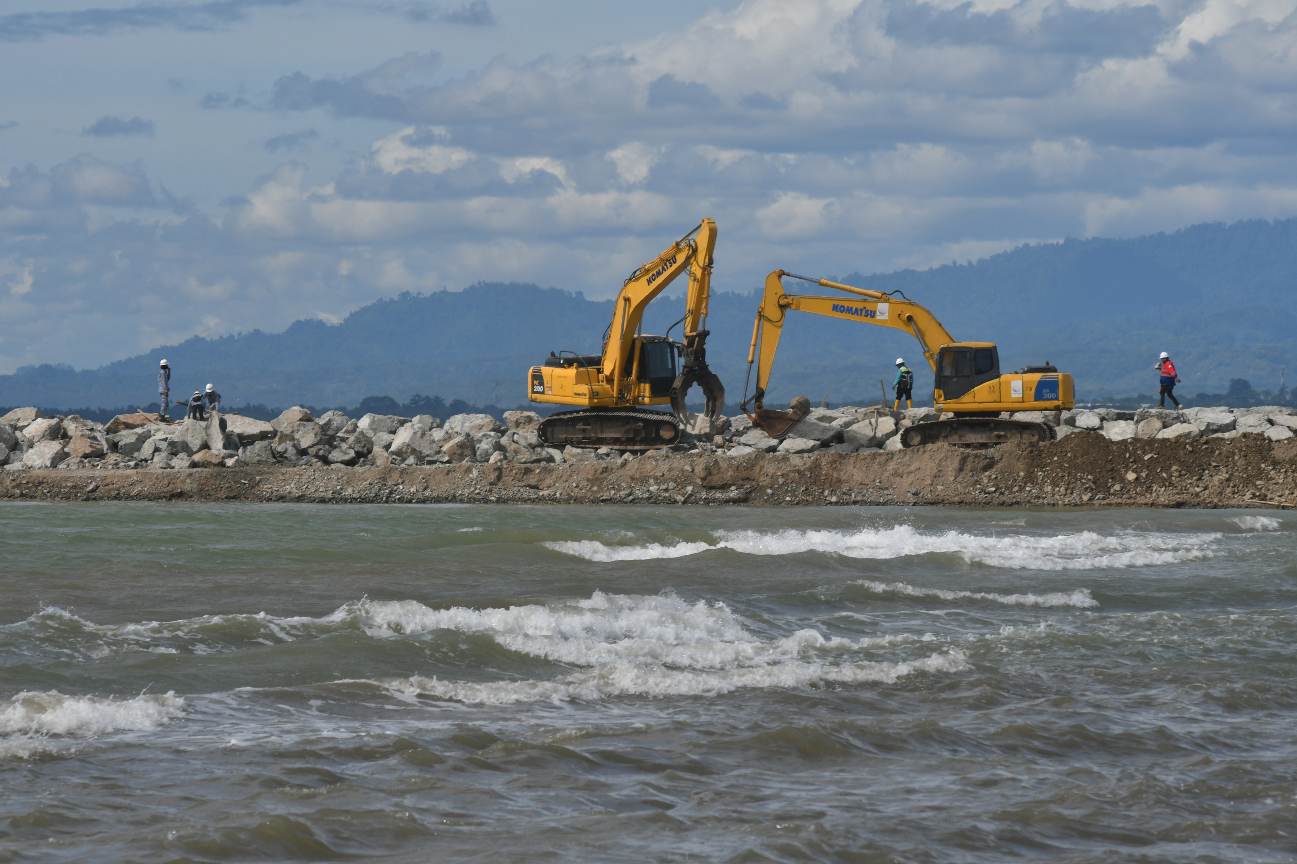Potret pekerja mengoperasikan alat berat pada pembanguunan di tepi pantai wilayah Sulawesi Tengah.