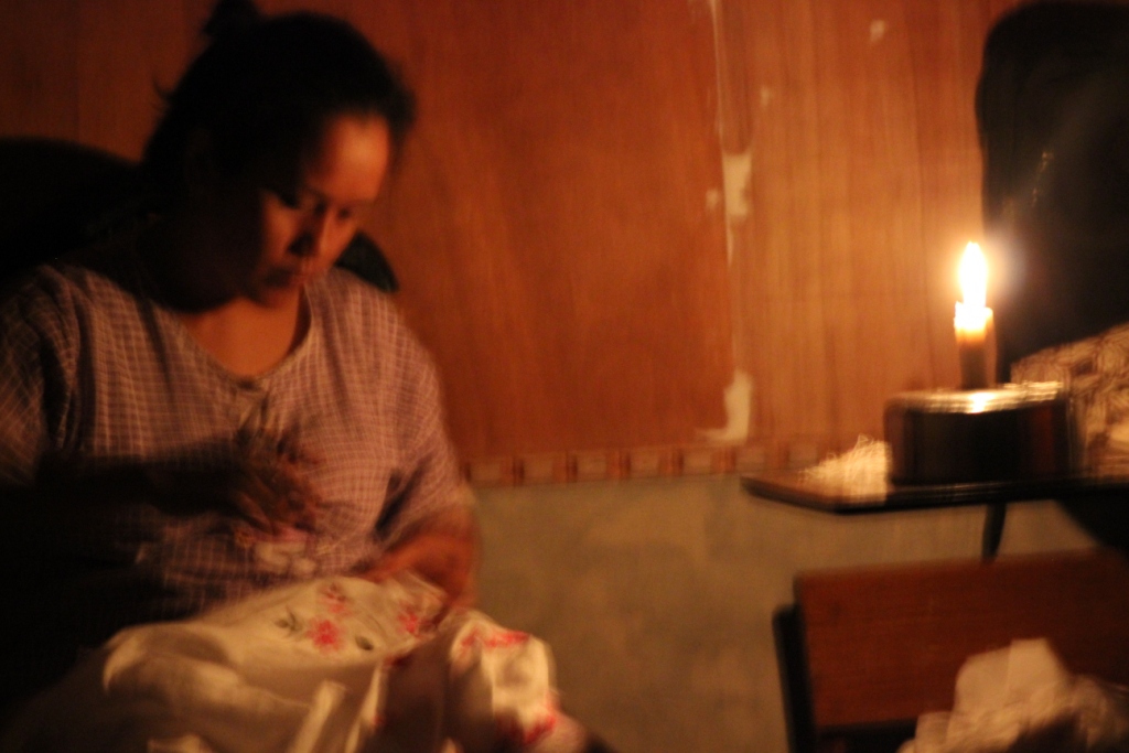 Warga bekerja diterangi lilin saat mati lampu.