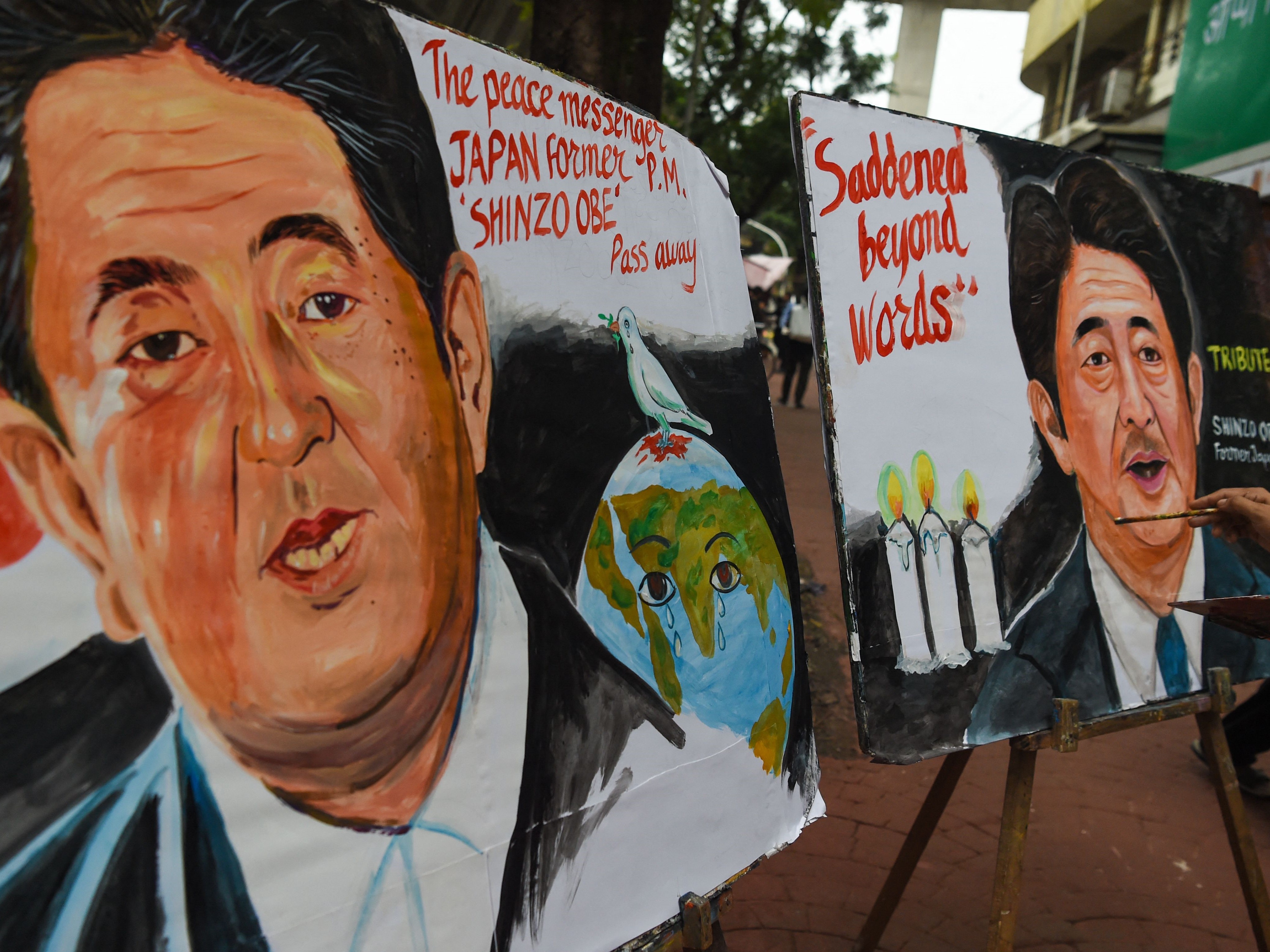 Seorang seniman memberikan sentuhan akhir pada lukisan mantan perdana menteri Jepang Shinzo Abe, di Mumbai pada 8 Juli 2022.