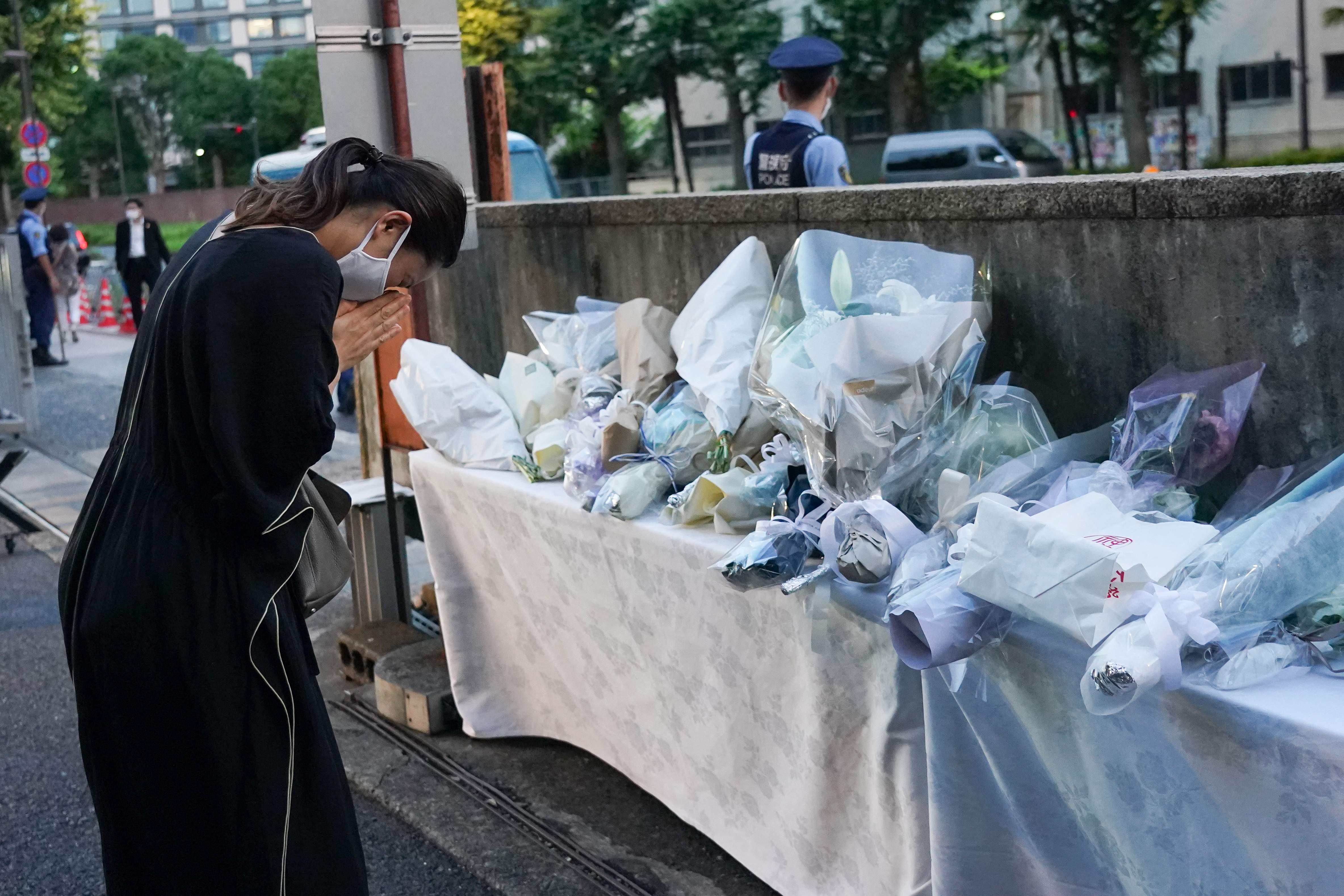 Seorang pelayat mempersembahkan bunga di dekat pintu masuk gedung markas Partai Demokrat Liberal (LDP) di Tokyo pada 10 Juli 2022, menyusul 