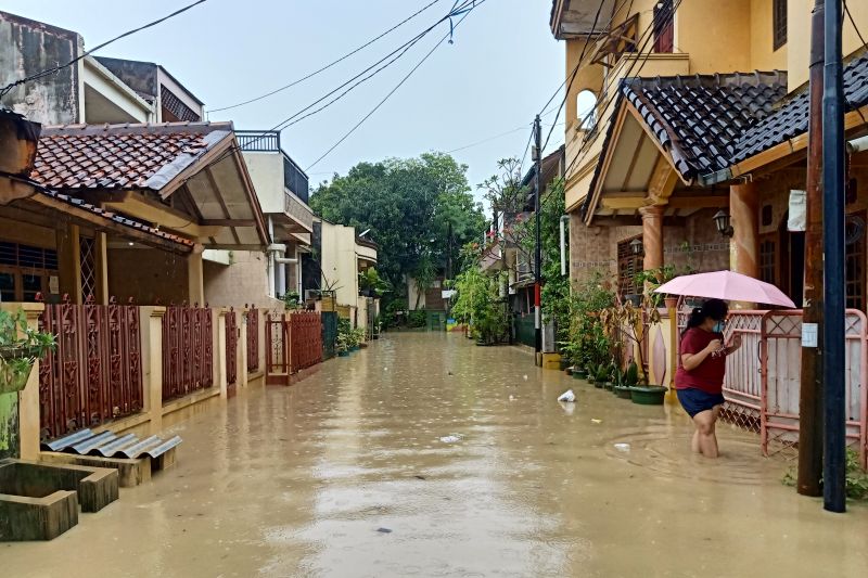Warga Perumahan Jaka Kencana melintas di lokasi banjir luapan Kali Bekasi yang dipicu tanggul jebol di Jalan Anggrek, Sabtu (16/7/2022)