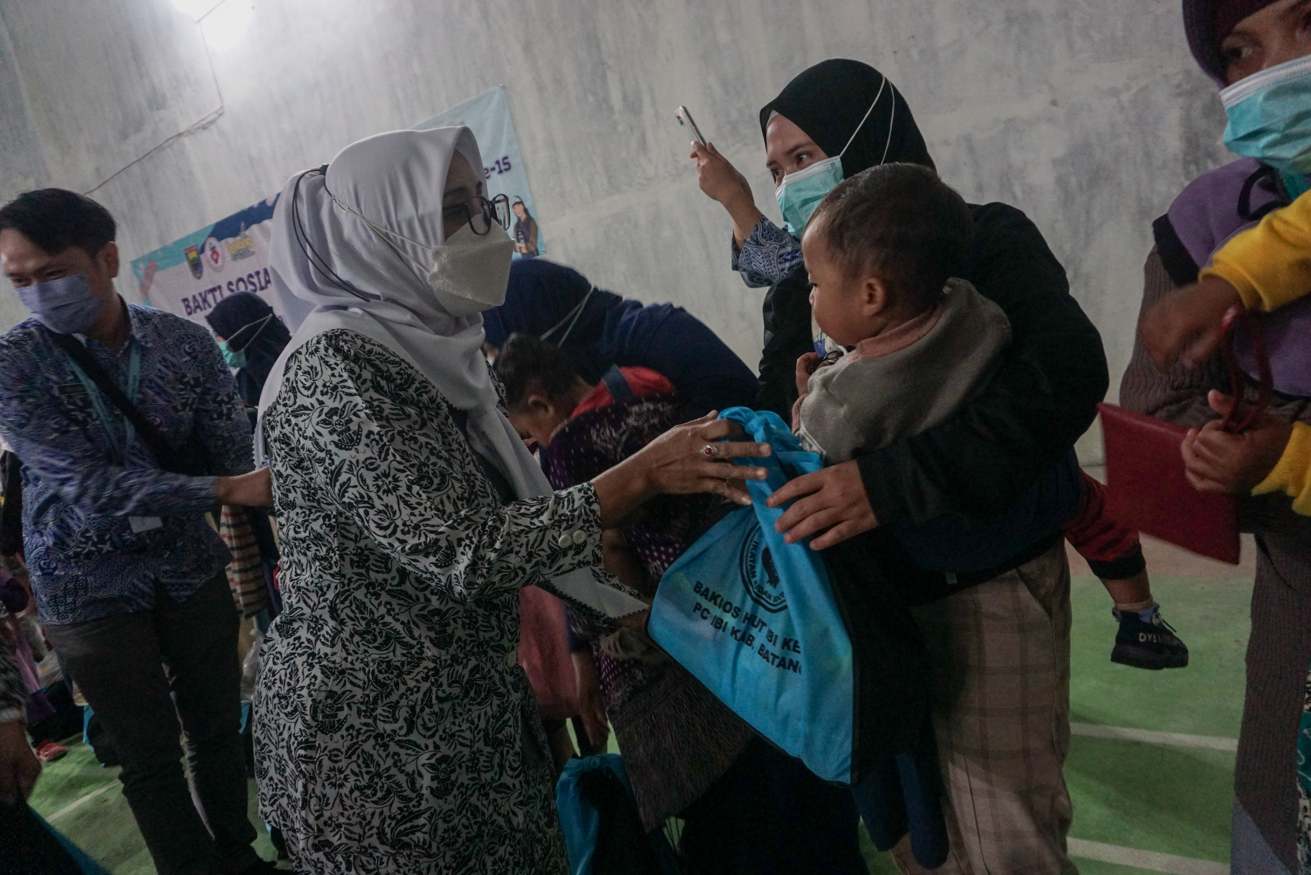 Ketua IBI Kabupaten Batang Suci Asih (kedua kiri) menyerahkan bantuan makanan sehat pada warga di Desa Gerlang, Batang, Rabu (13/7/2022)