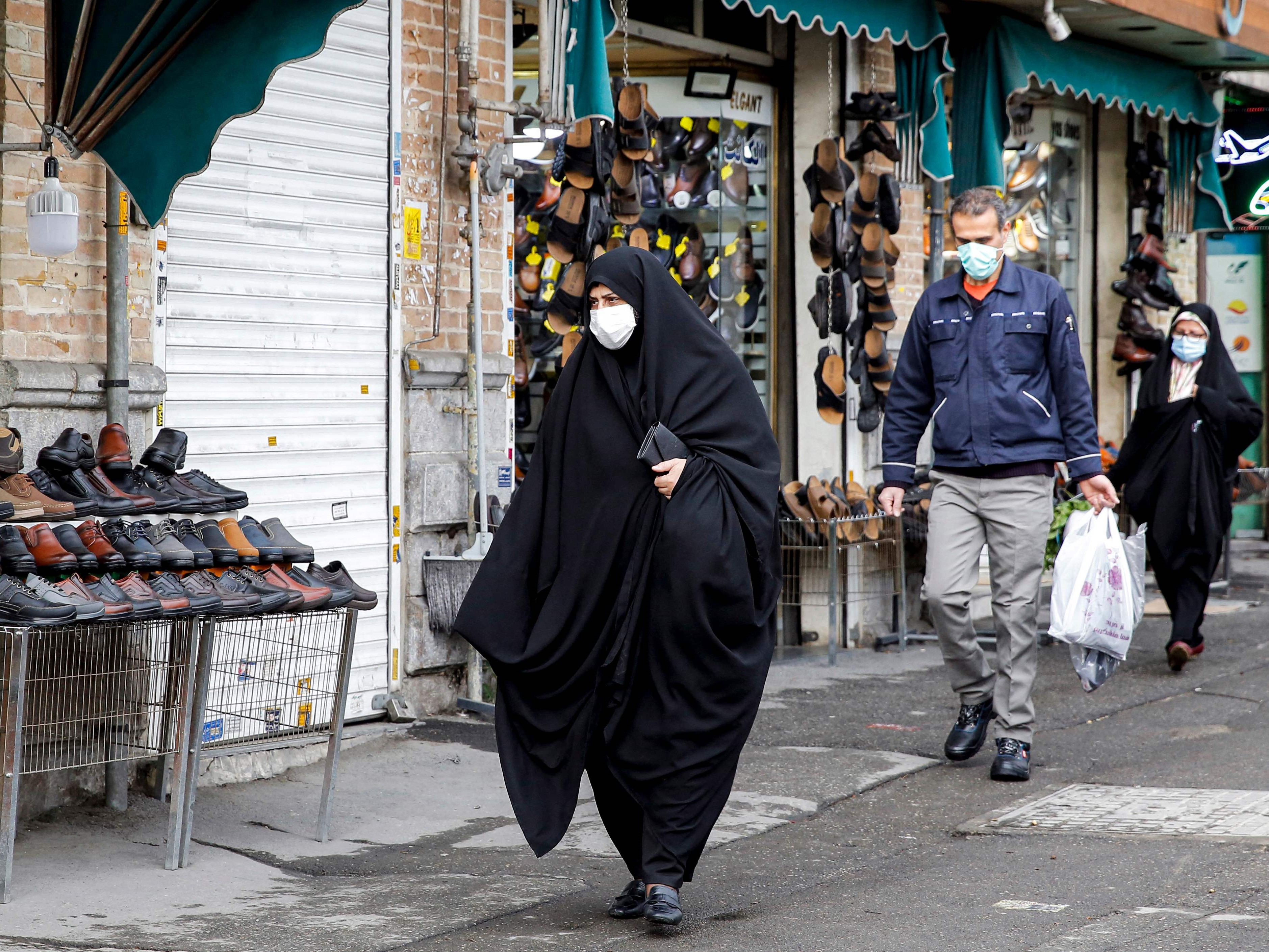 Seorang wanita berjalan melewati toko penjual sepatu di selatan ibu kota Teheran, 20 Februari 2022.