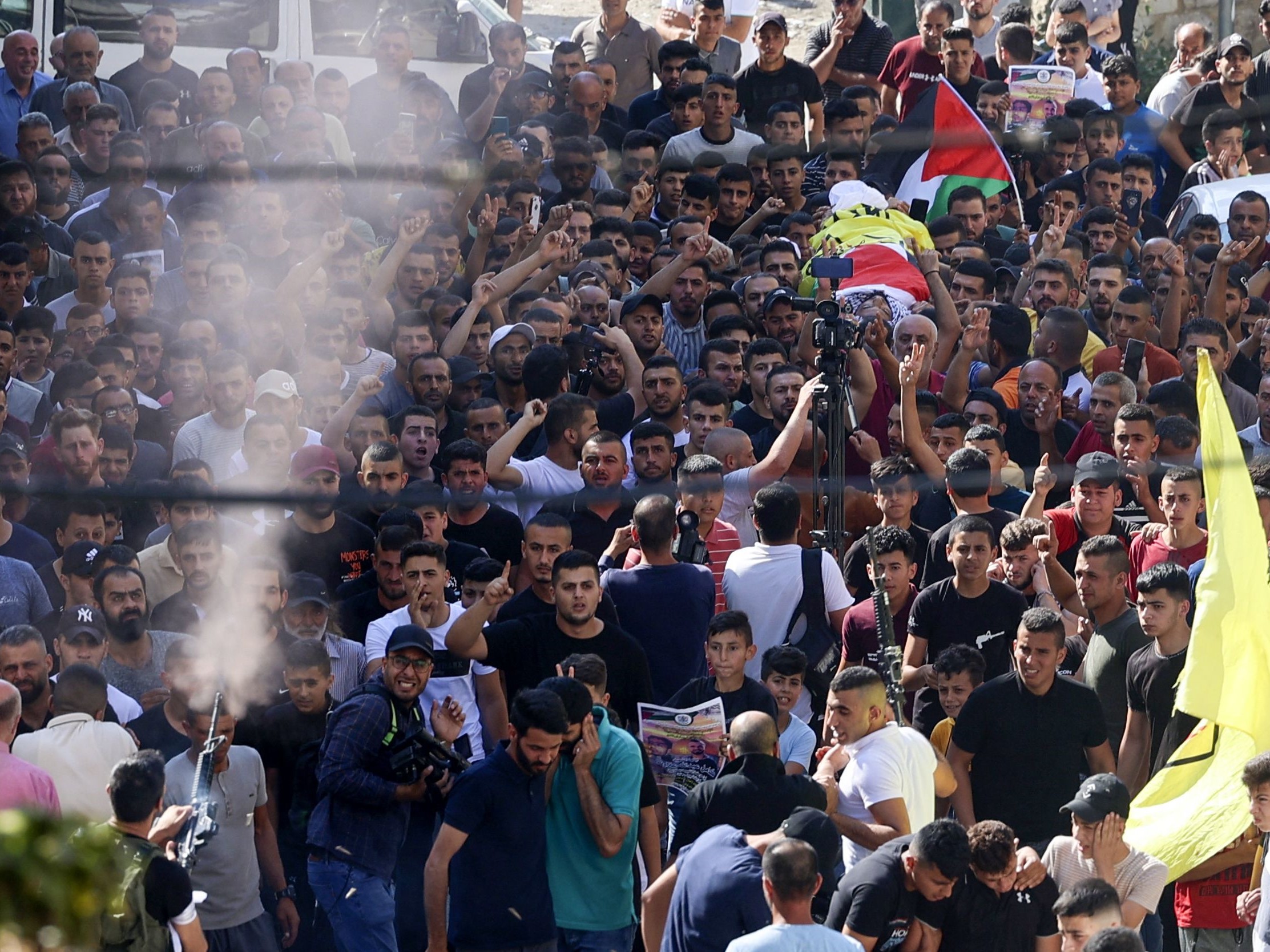 Seorang pria menembak ke udara adalah pelayat membawa tubuh Kamel Alawnah 17 tahun selama pemakamannya di desa Tepi Barat Jaba, utara Jenin.