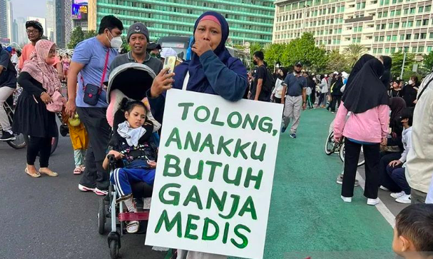 Dokumentasi unggahan foto seorang ibu membawa poster bertuliskan 