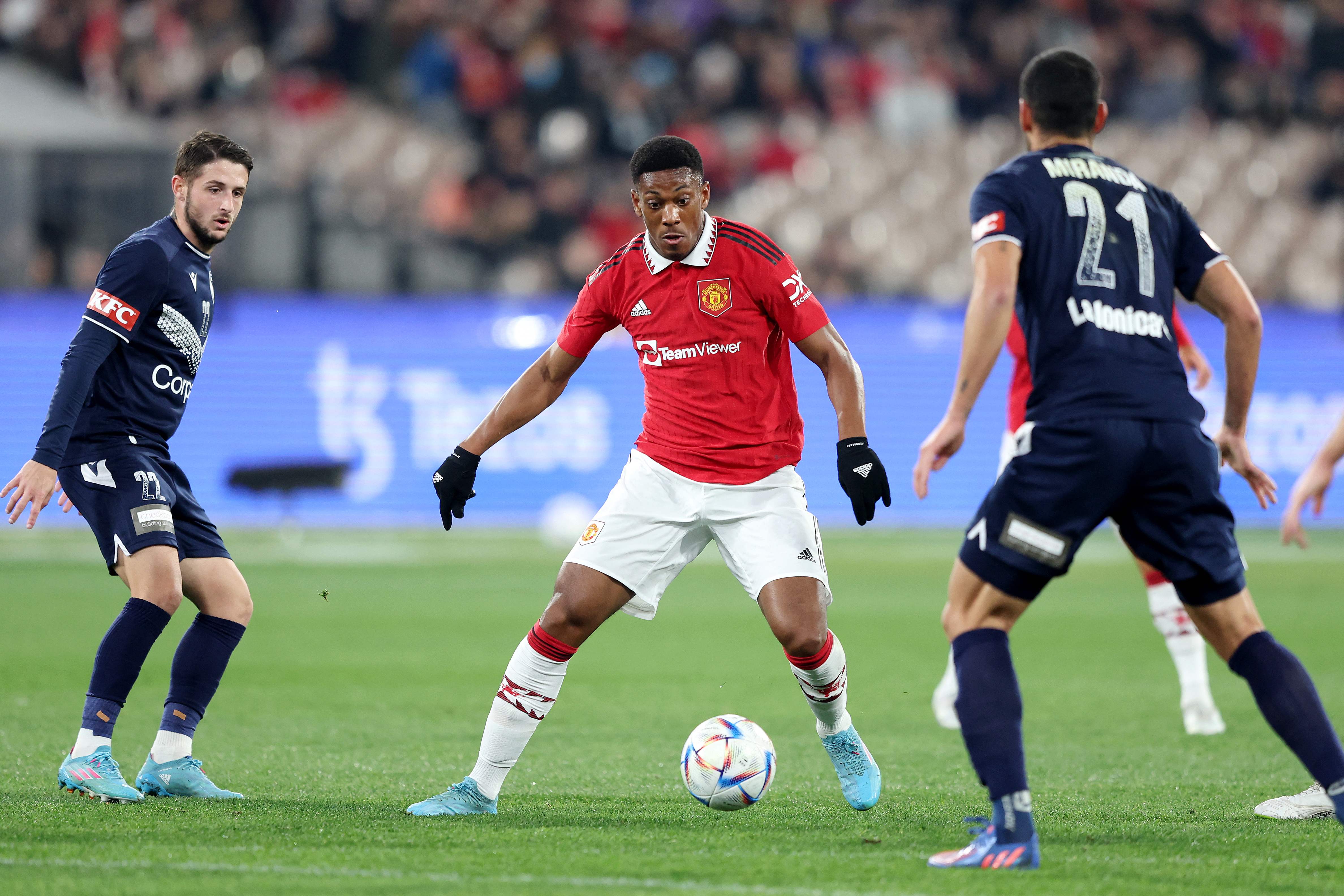 Pemain  Manchester United, Anthony Martial, membawa bola dengan dibayangi dua pemain Melbourne Victory pada laga ekshibisi di Australia.
