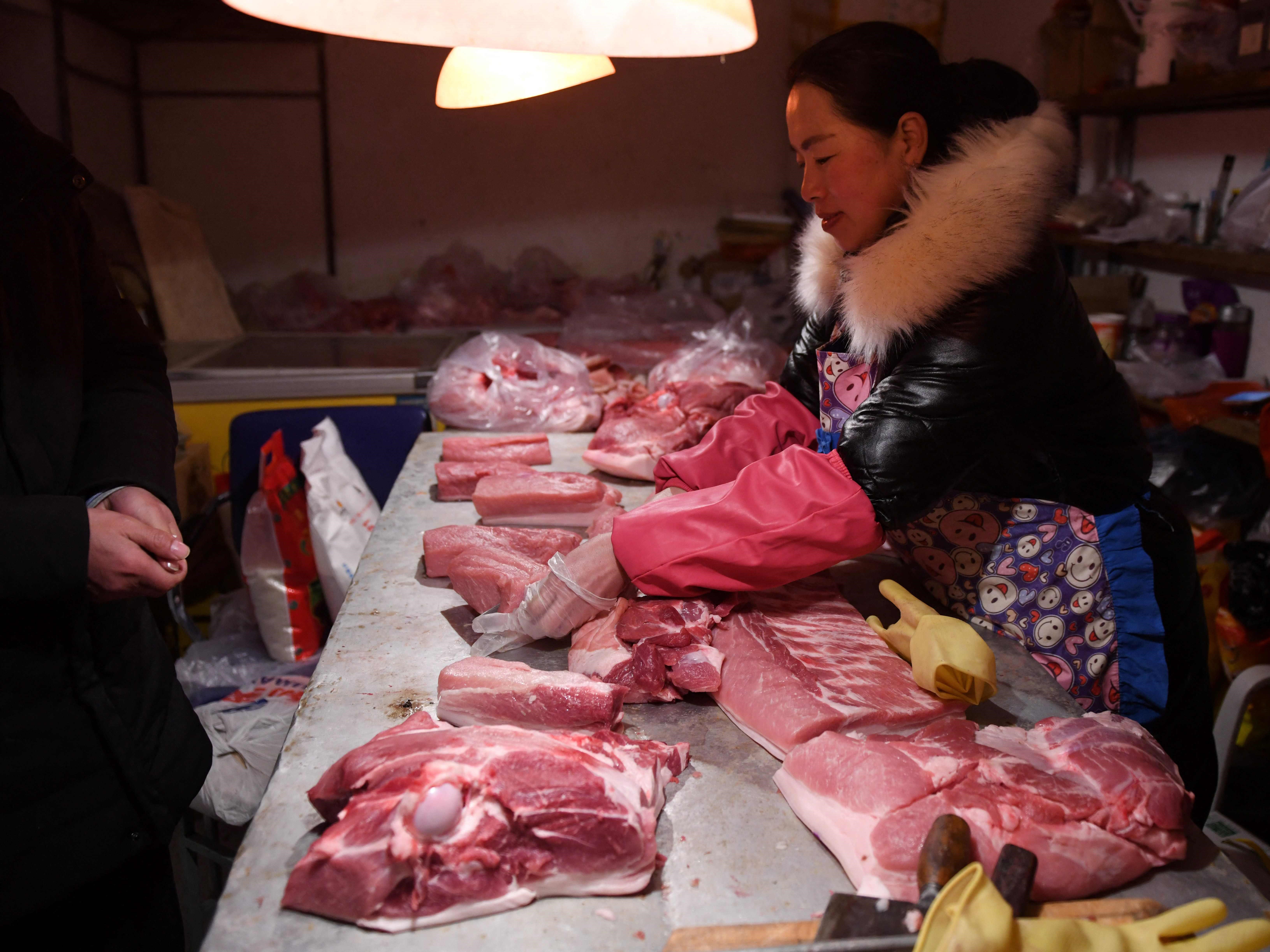 Seorang tukang daging menyiapkan daging babi untuk seorang pelanggan di desa Datai, sebelah barat Beijing.