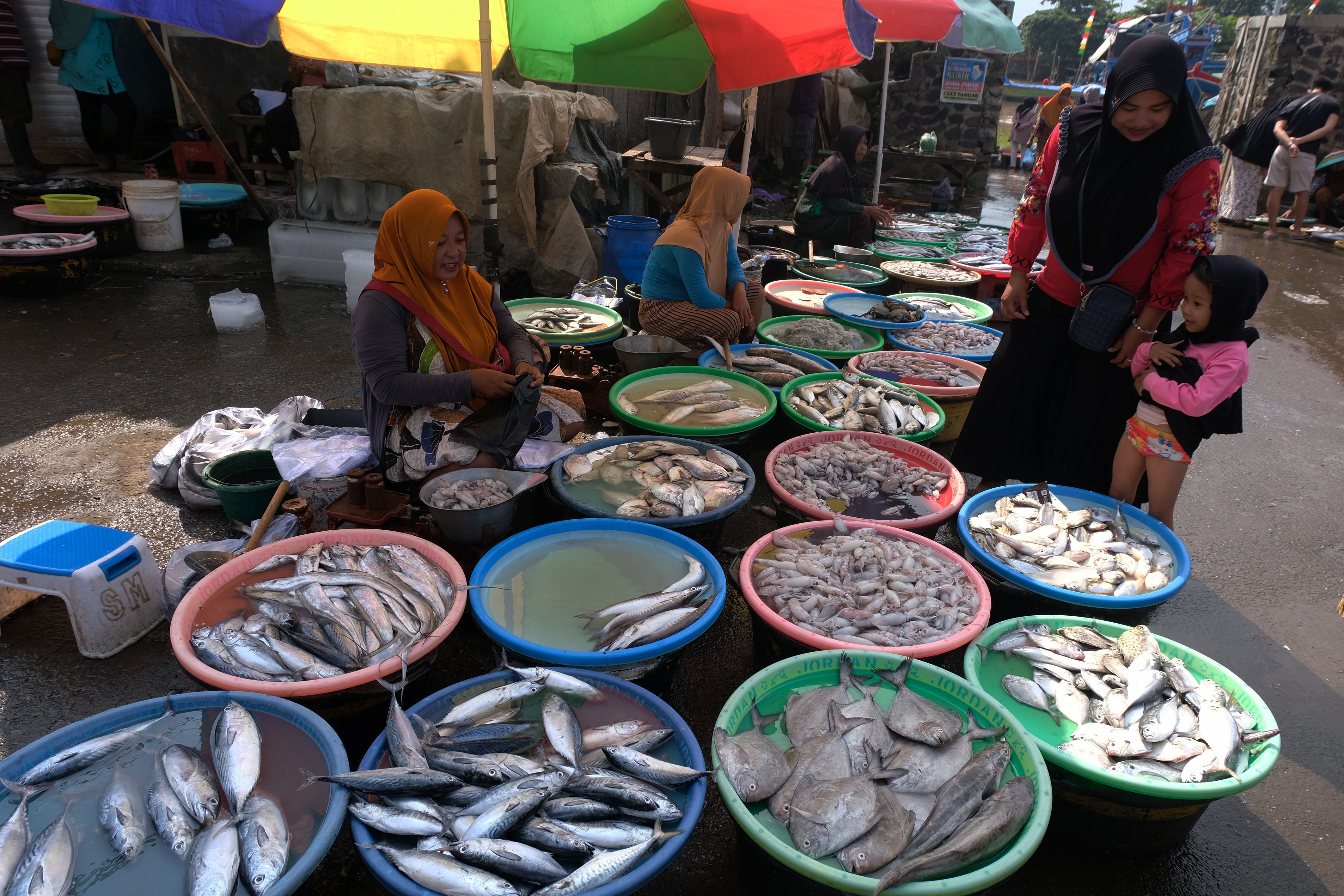 Pedagang melayani pembeli ikan laut segar di pasar wilayah Jawa Tengah.