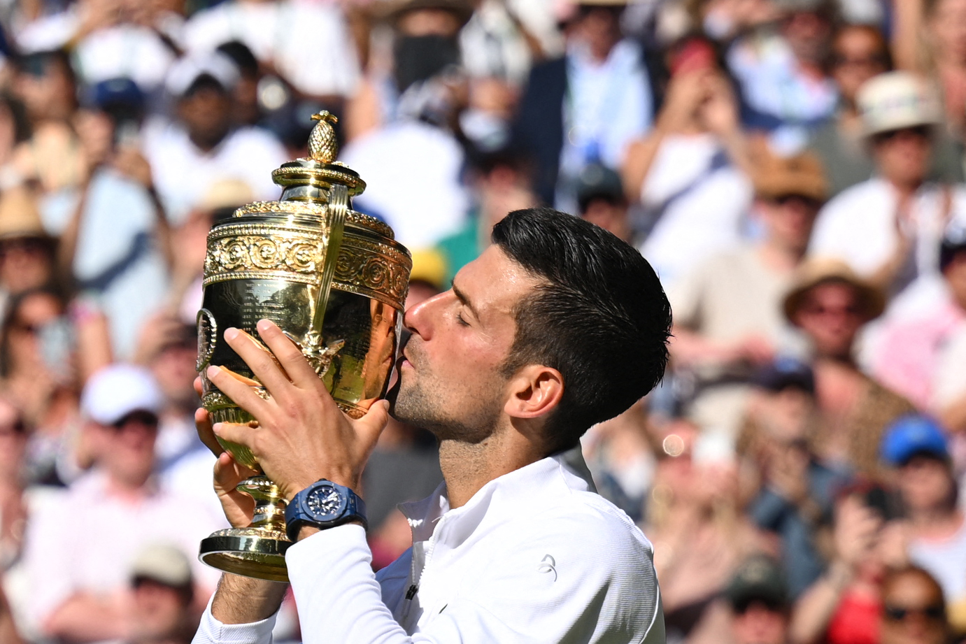 Petenis Serbia Novak Djokovic mencium trofi Wimbledon yang diraihnya setelah mengalahkan Nick Kyrgios di laga final, Minggu (10/7).