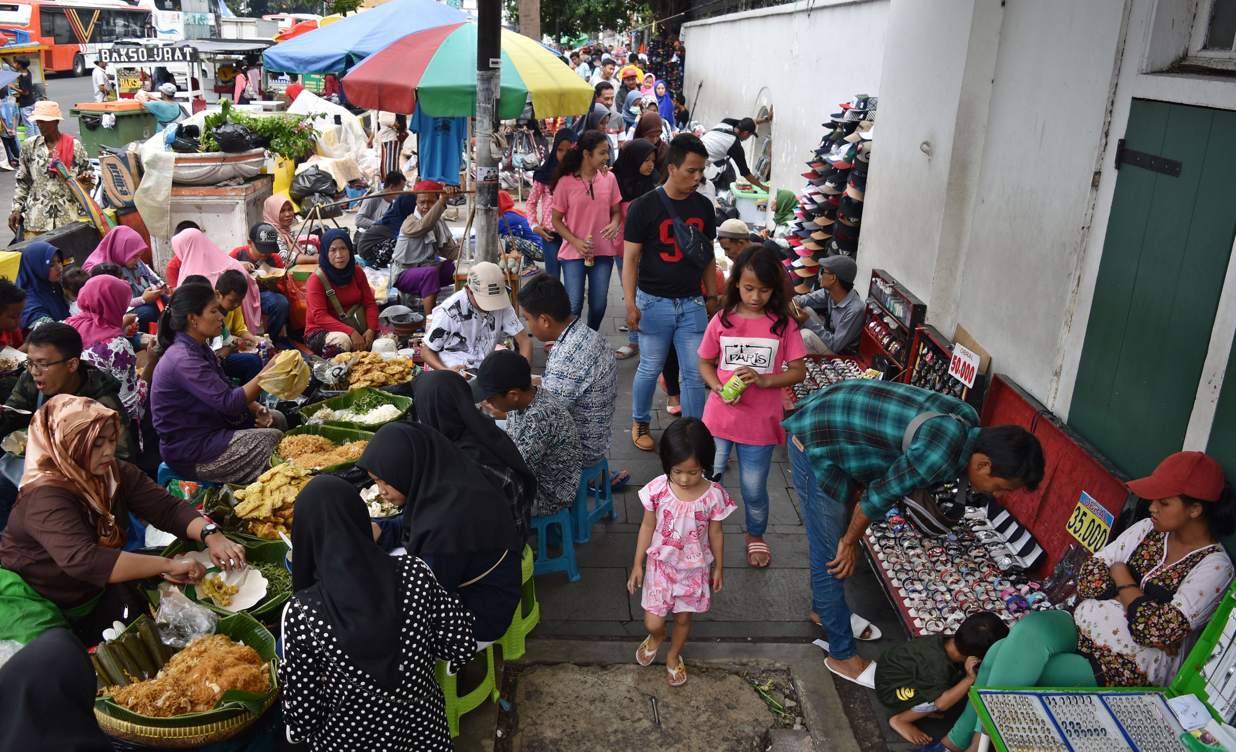 Warga berjalan di trotoar yang menjadi lokasi berjualan pedagang kaki lima (PKL) di kawasan Kota Tua, Jakarta, Sabtu (20/4/2019).