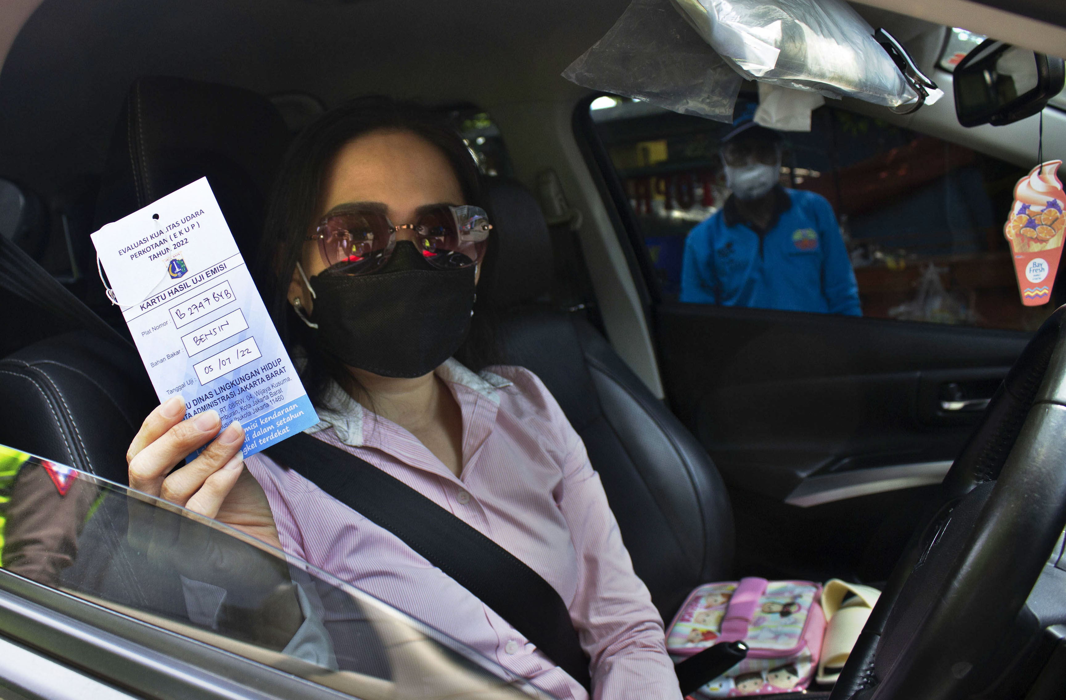 Seorang pengendara menunjukkan kartu hasil uji emisi di Jakarta
