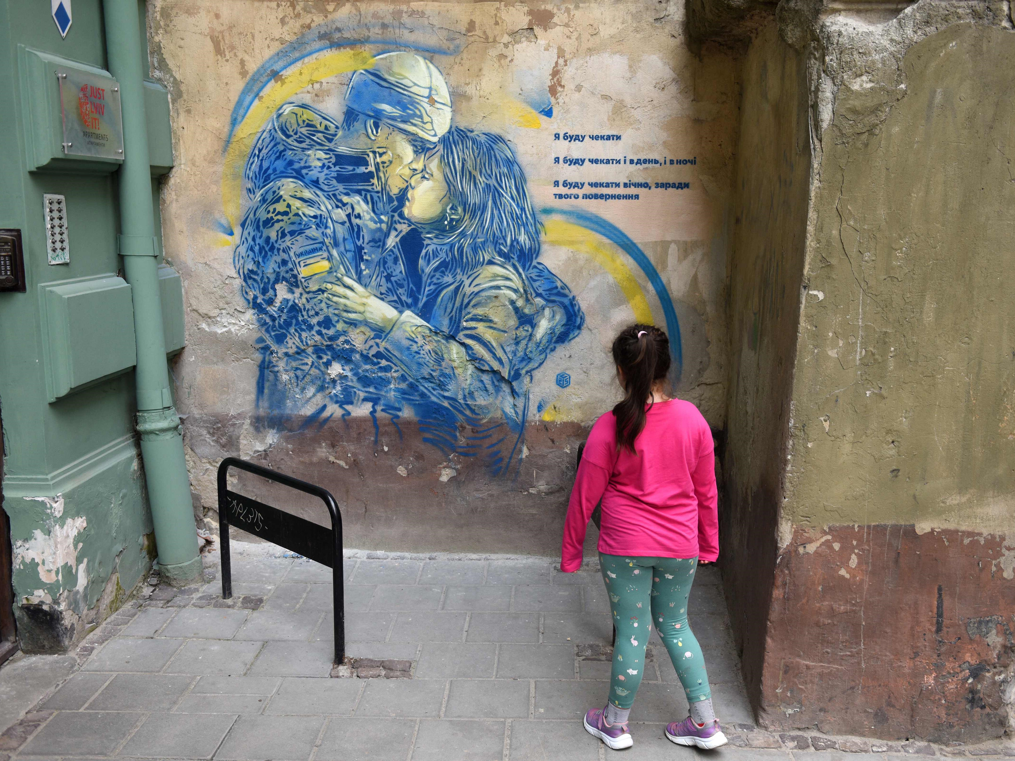 Seorang anak melihat lukisan dinding karya seniman jalanan Christian Guemy di kota Lviv, Ukraina barat.