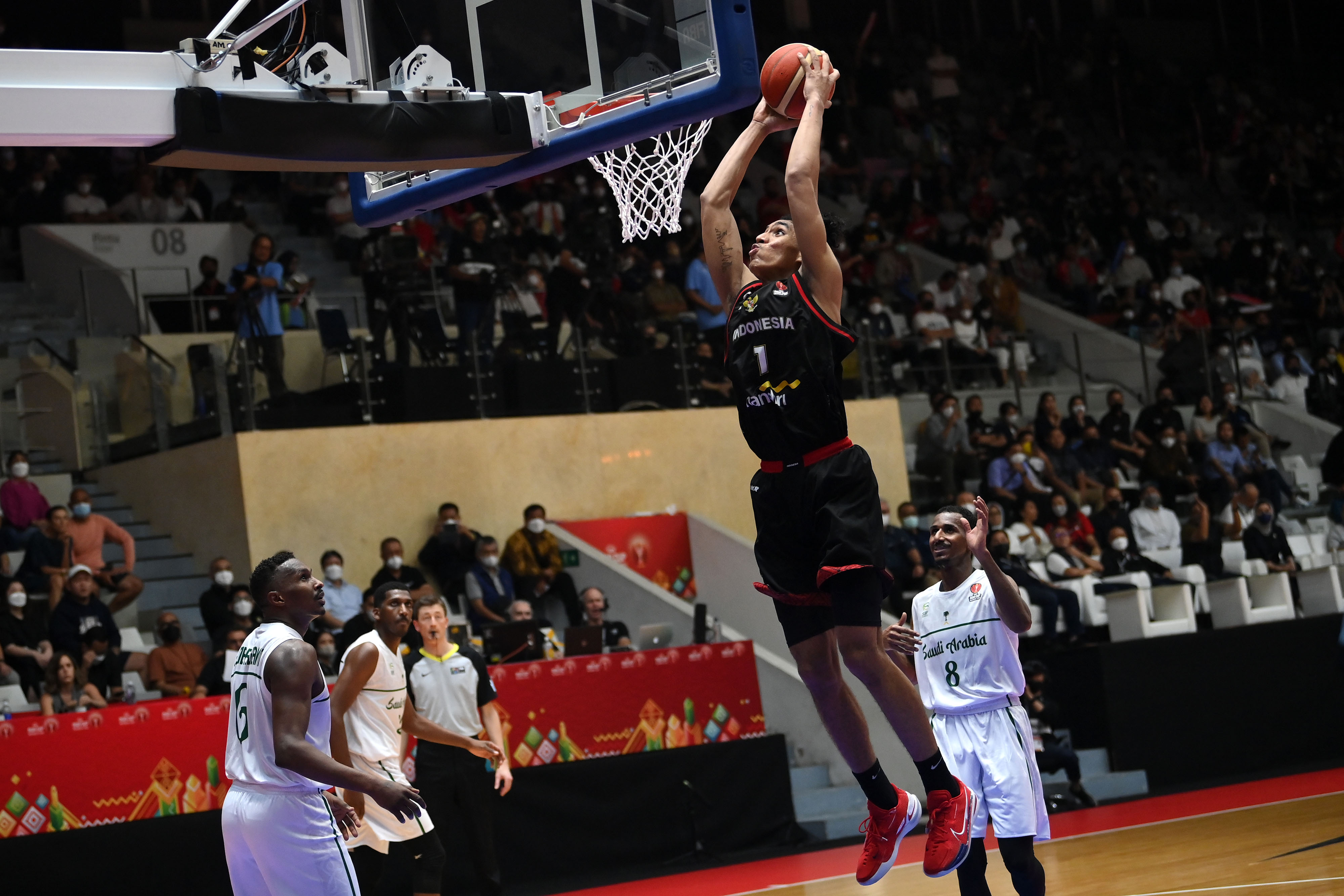 Pebasket Indonesia Derrick Michael melakukan 'slam dunk' ke ring timnas Arab Saudi.