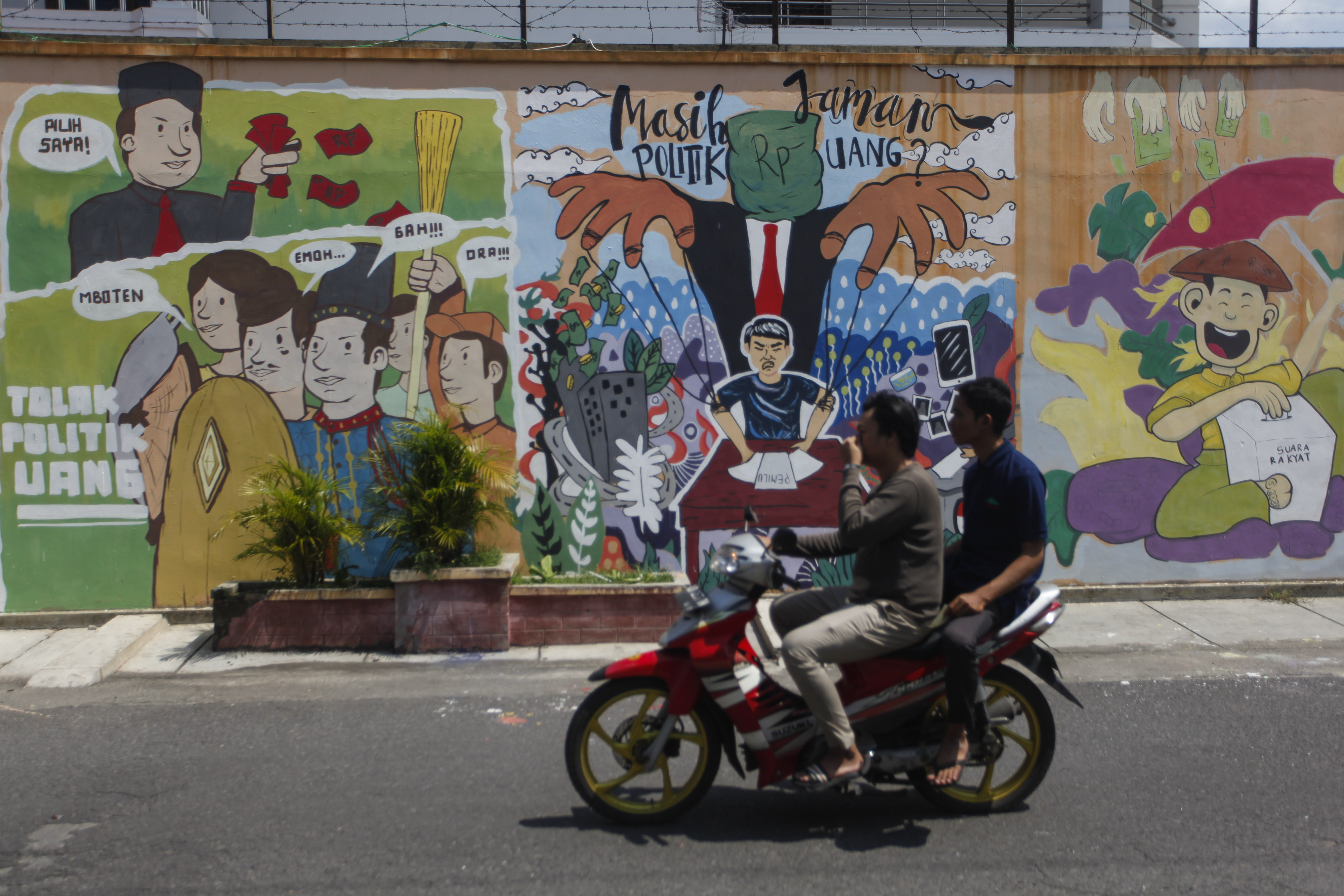 Warga melintasi mural bertema pemilu di wilayah Solo, Jawa Tengah.