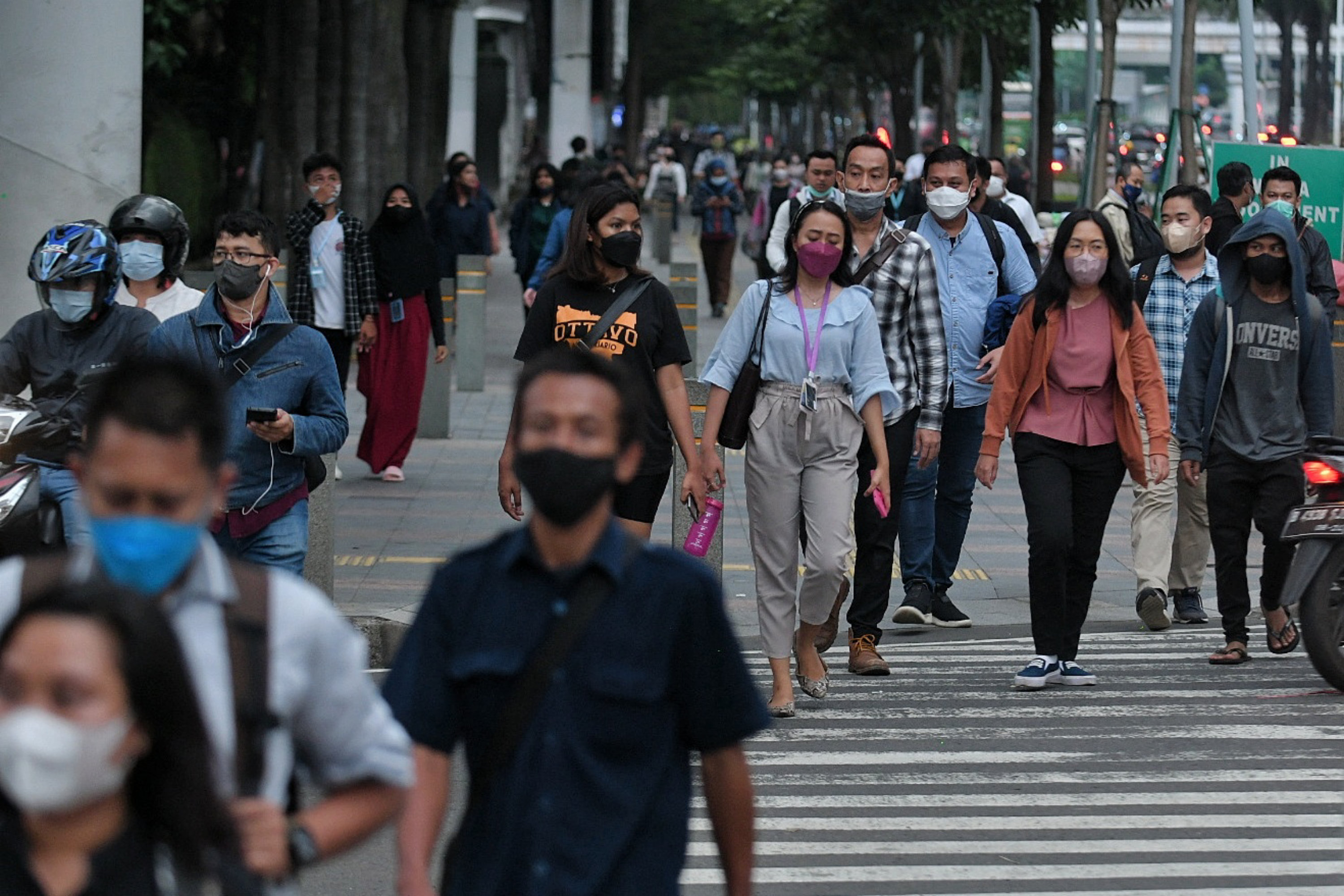 Pekerja berjalan di trotoar kawasan jalan Sudirman, Jakarta.