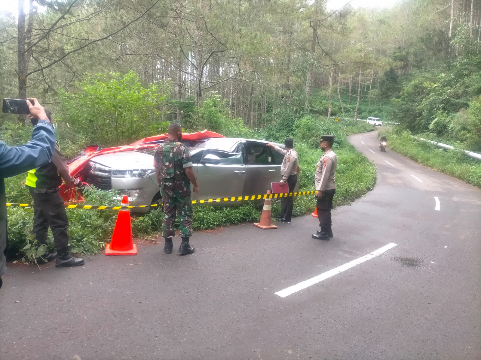 Petugas kepolisian dibantu TNI dan warga mengevakuasi pengemudi mobil yang tertimpa pohon tumbang di Kabupaten Tasikmalaya, Jumat (15/7).