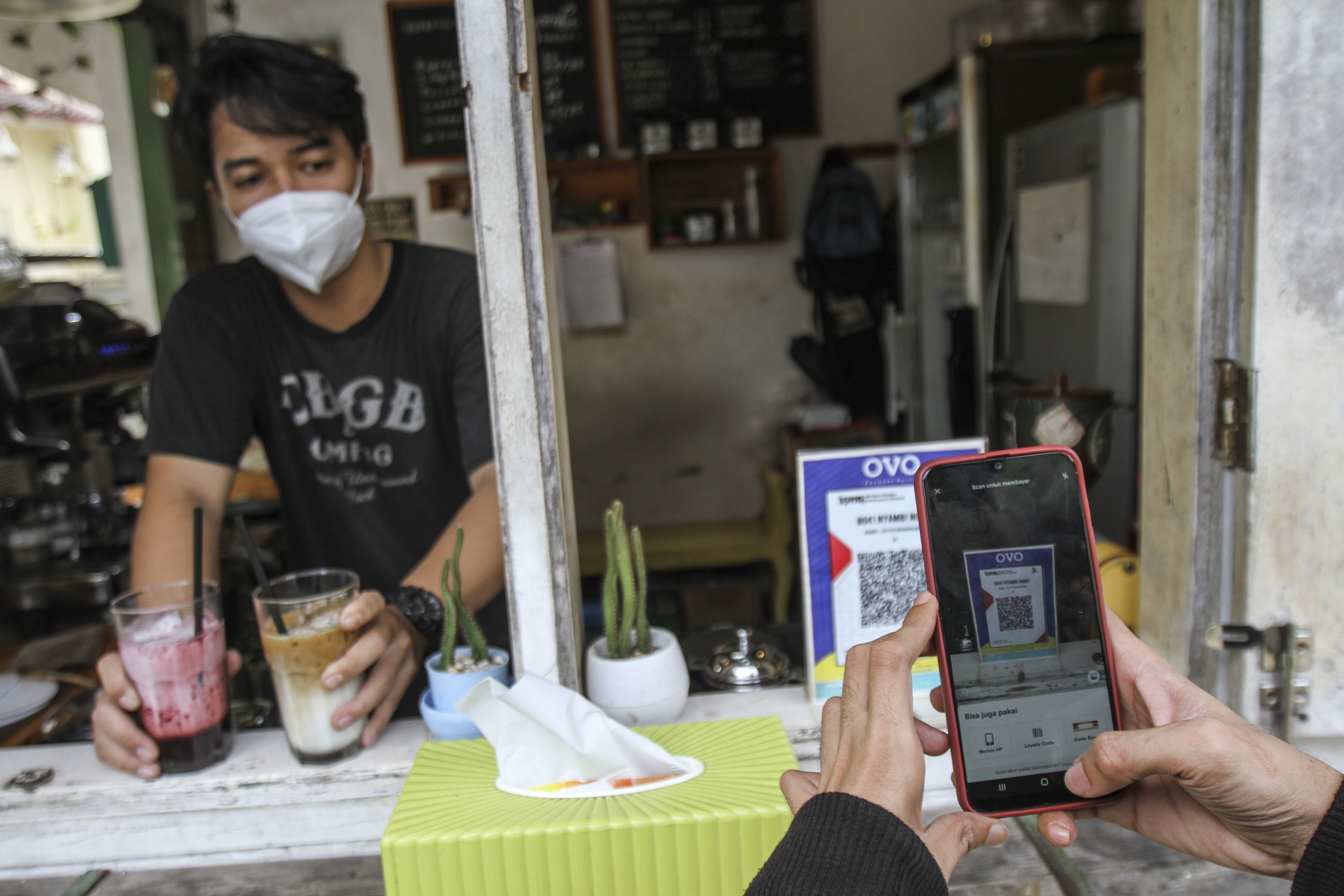 Pembeli membeli kopi dengan memanfaatkan fasilitas QRIS.