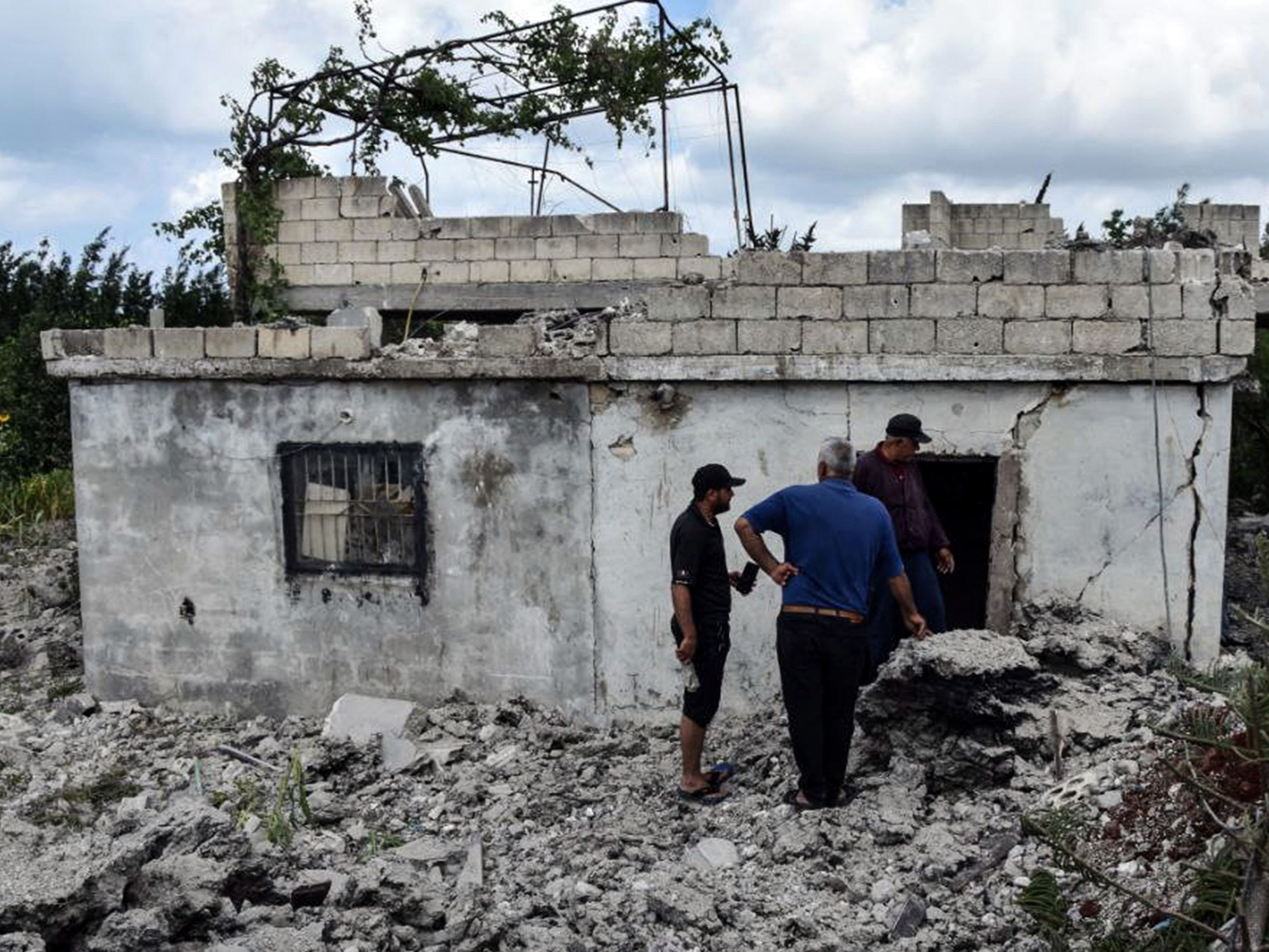 Orang-orang menilai kerusakan bangunan oleh serangan udara Israel yang dilaporkan di kota pesisir barat Suriah, Tartus.