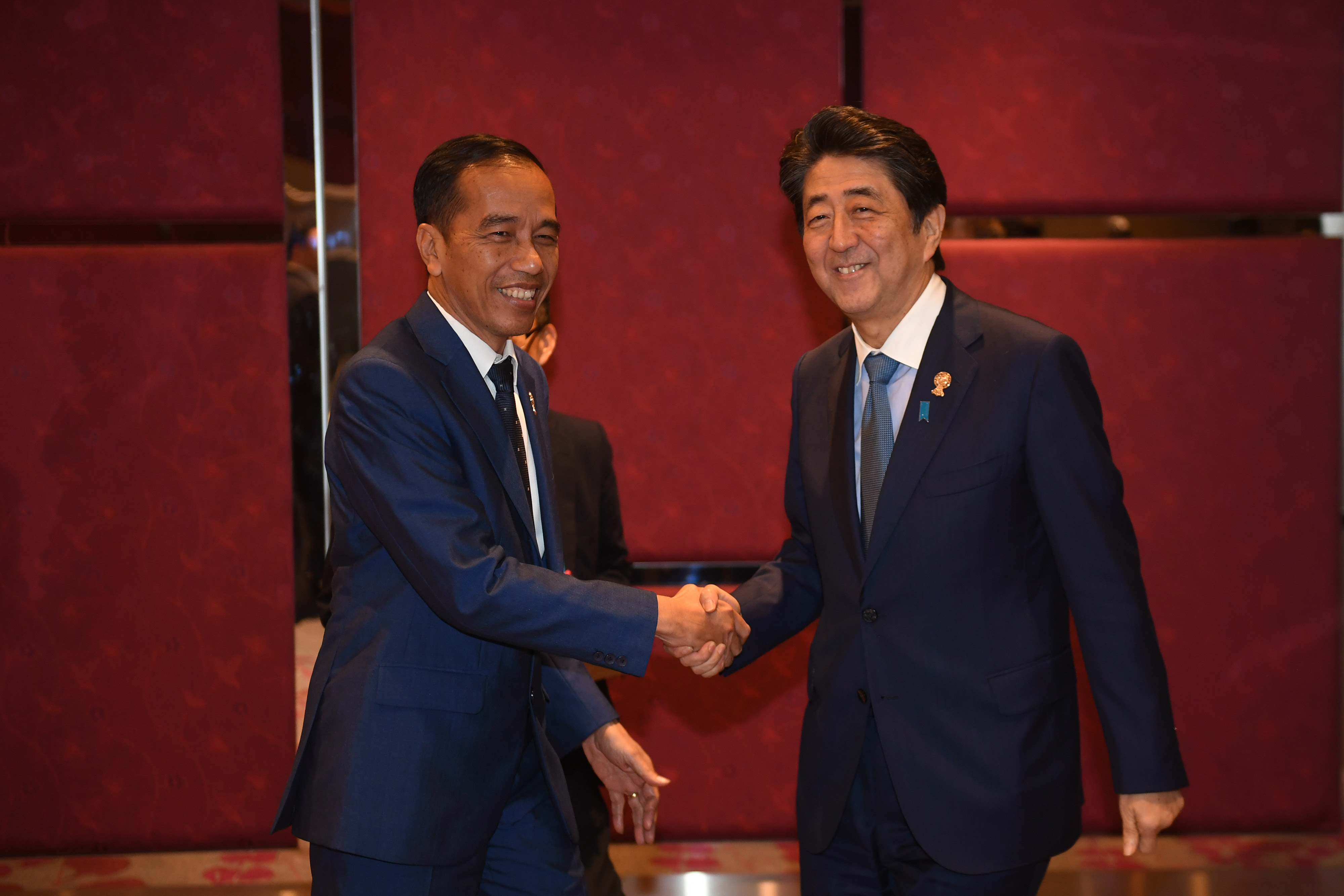 Presiden Joko Widodo (kiri) berjabat tangan dengan Shinzo Abe (kanan) saat masih menjabat sebagai Perdana Menteri Jepang pada 2019.