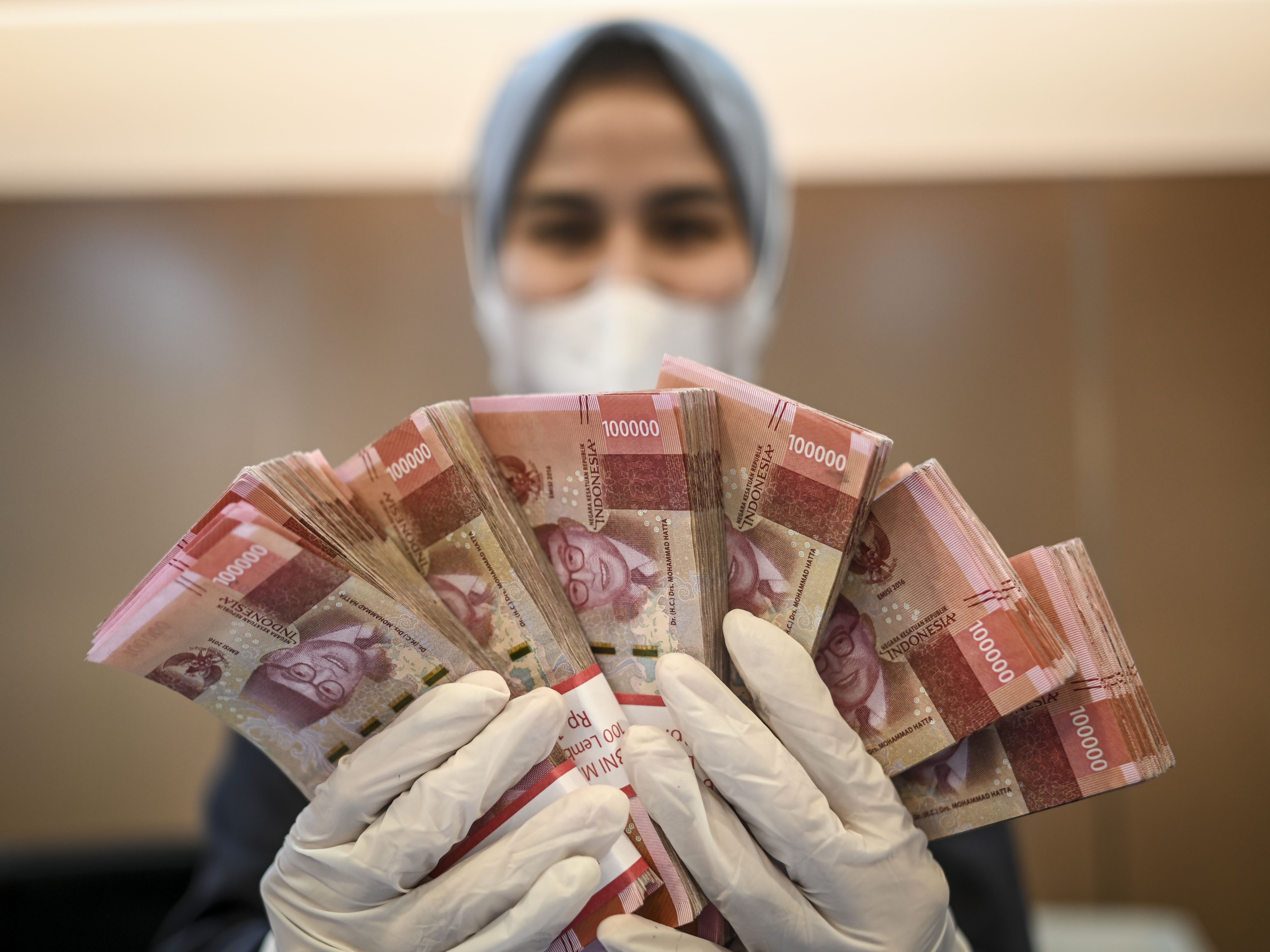 Petugas bank menunjukkan uang di BNI KC Mega Kuningan, Jakarta, Selasa (28/6/2022).