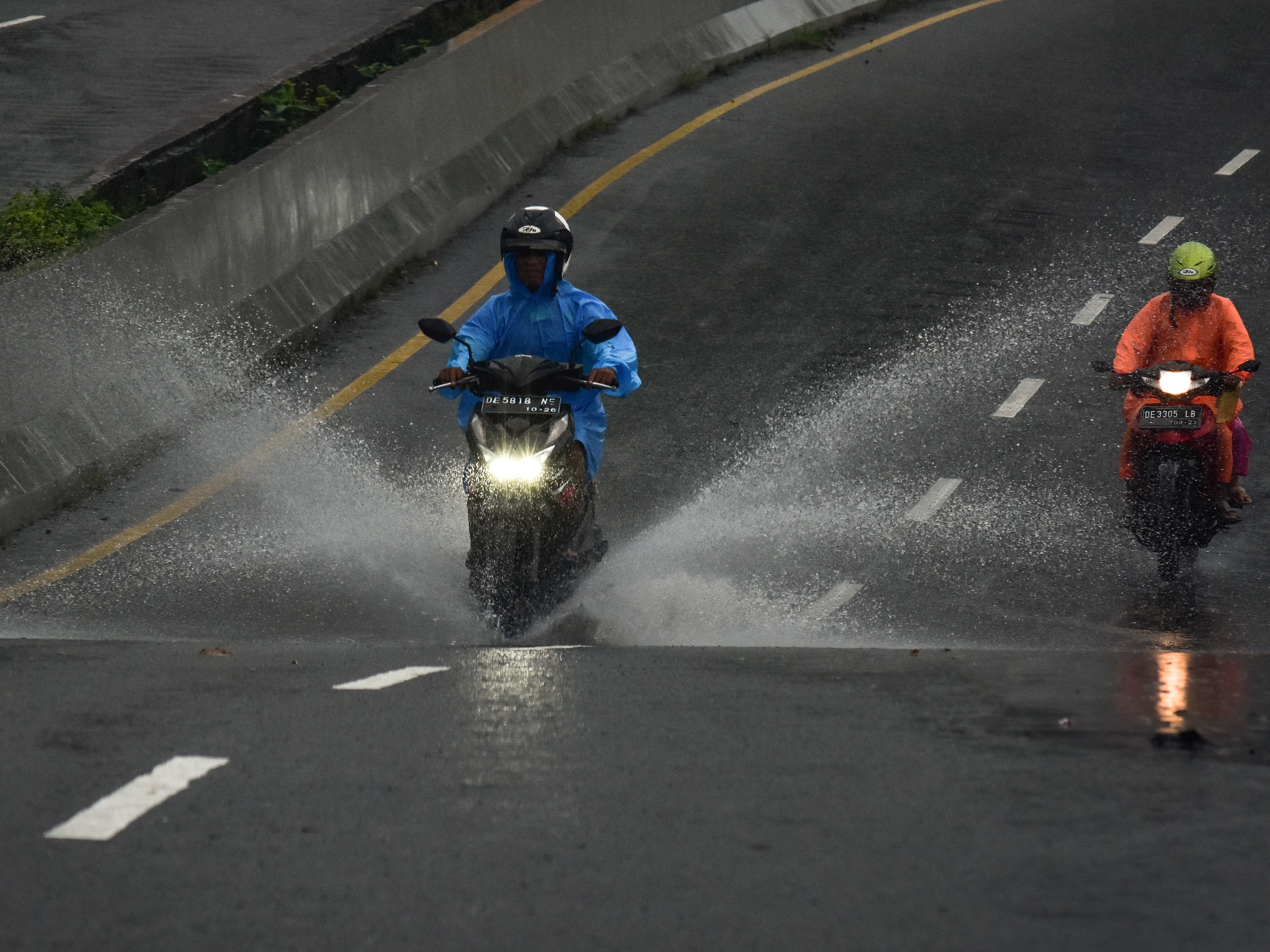 Dua pengendara melaju menembus hujan di Jalan Jenderal Sudirman, Kota Ambon, Maluku, Senin (11/7/2022).