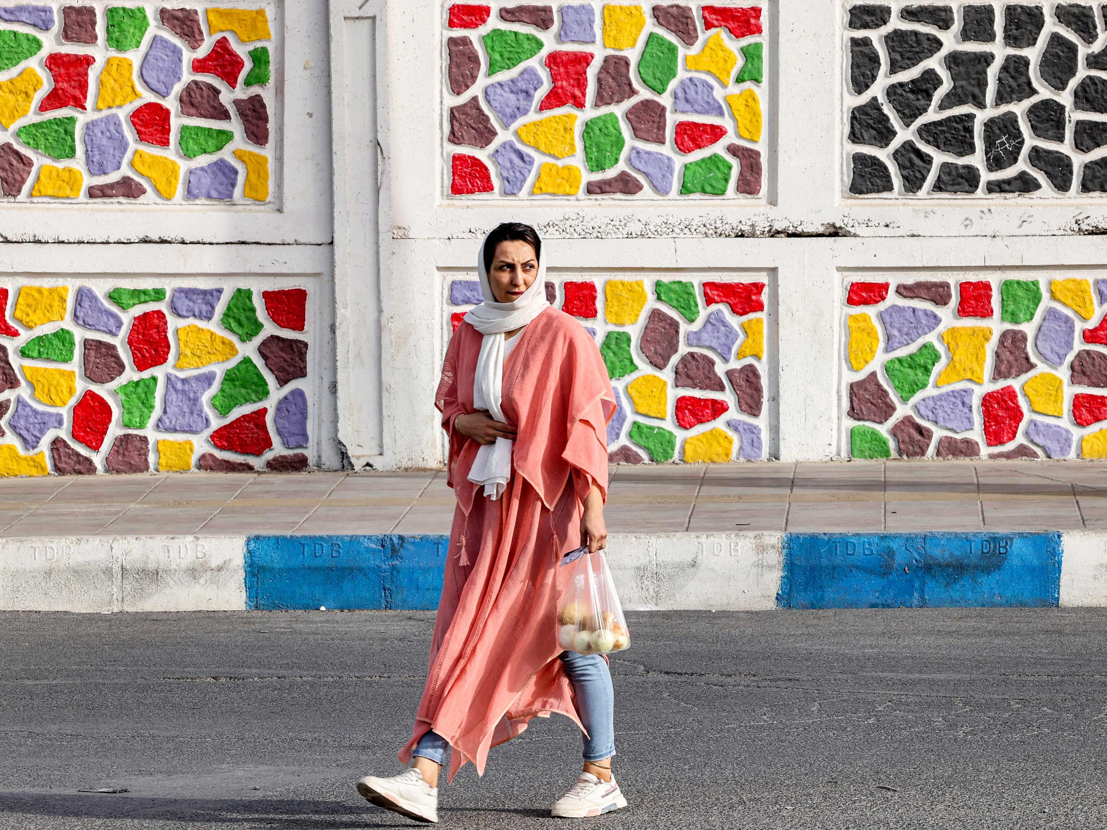 Seorang wanita berjalan di sepanjang jalan saat badai pasir di selatan ibu kota Teheran pada 4 Juli 2022. 