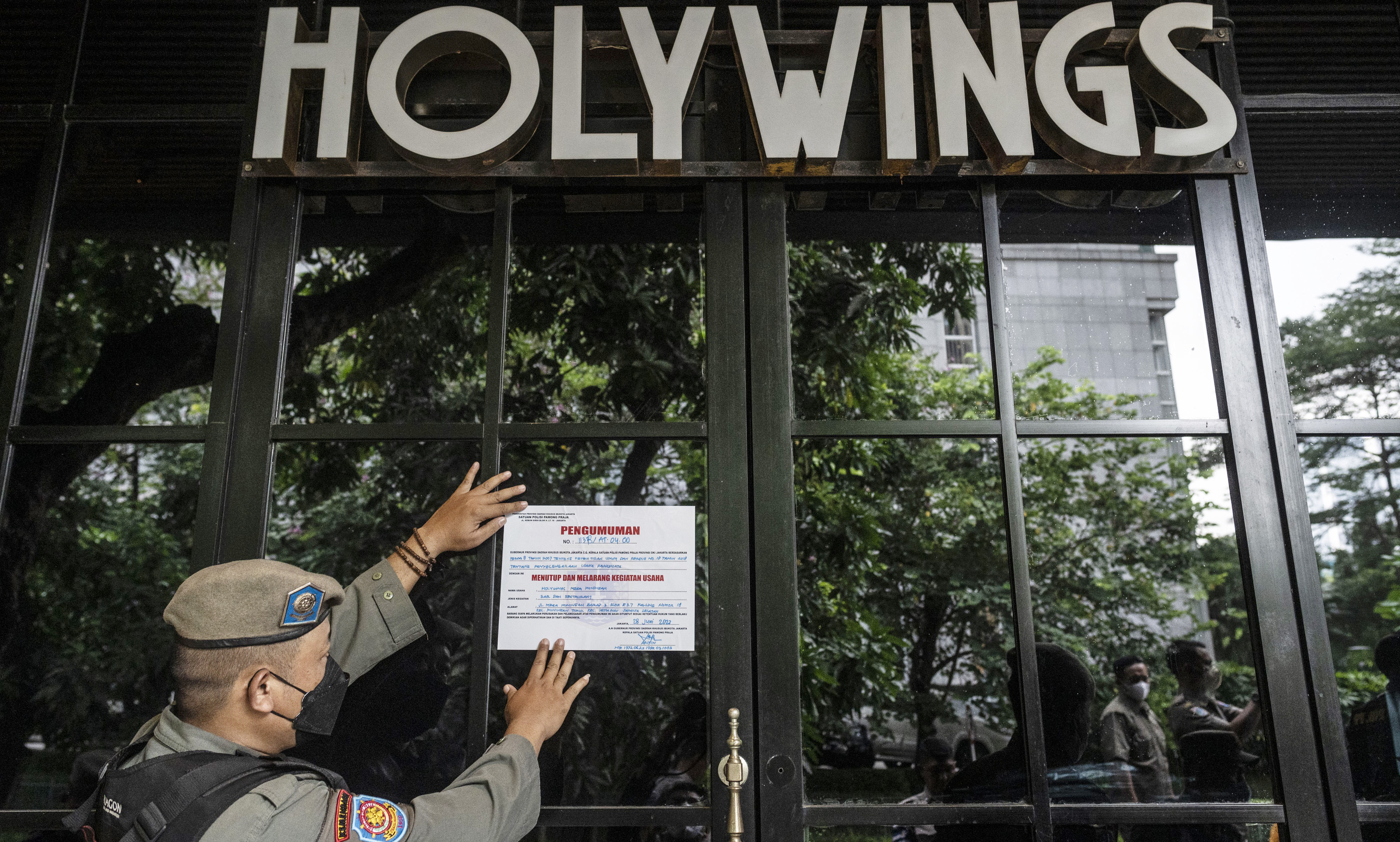 Satpol PP memasang stiker penyegelan outlet Holywings di kawasan Mega Kuningan, Jakarta.