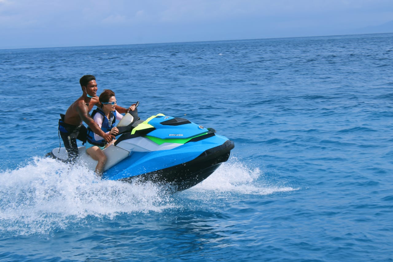 Seorang wisman dipandu profesional sedang menikmati wahana jetski di perairan Pulau Nusa Penida, Bali.