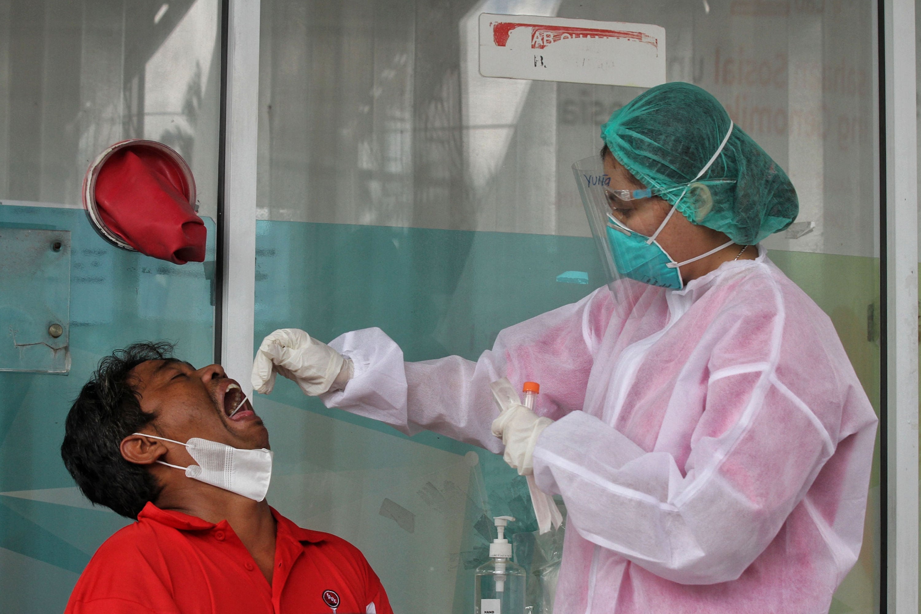 Tenaga kesehatan melakukan tes usap PCR terhadap warga.
