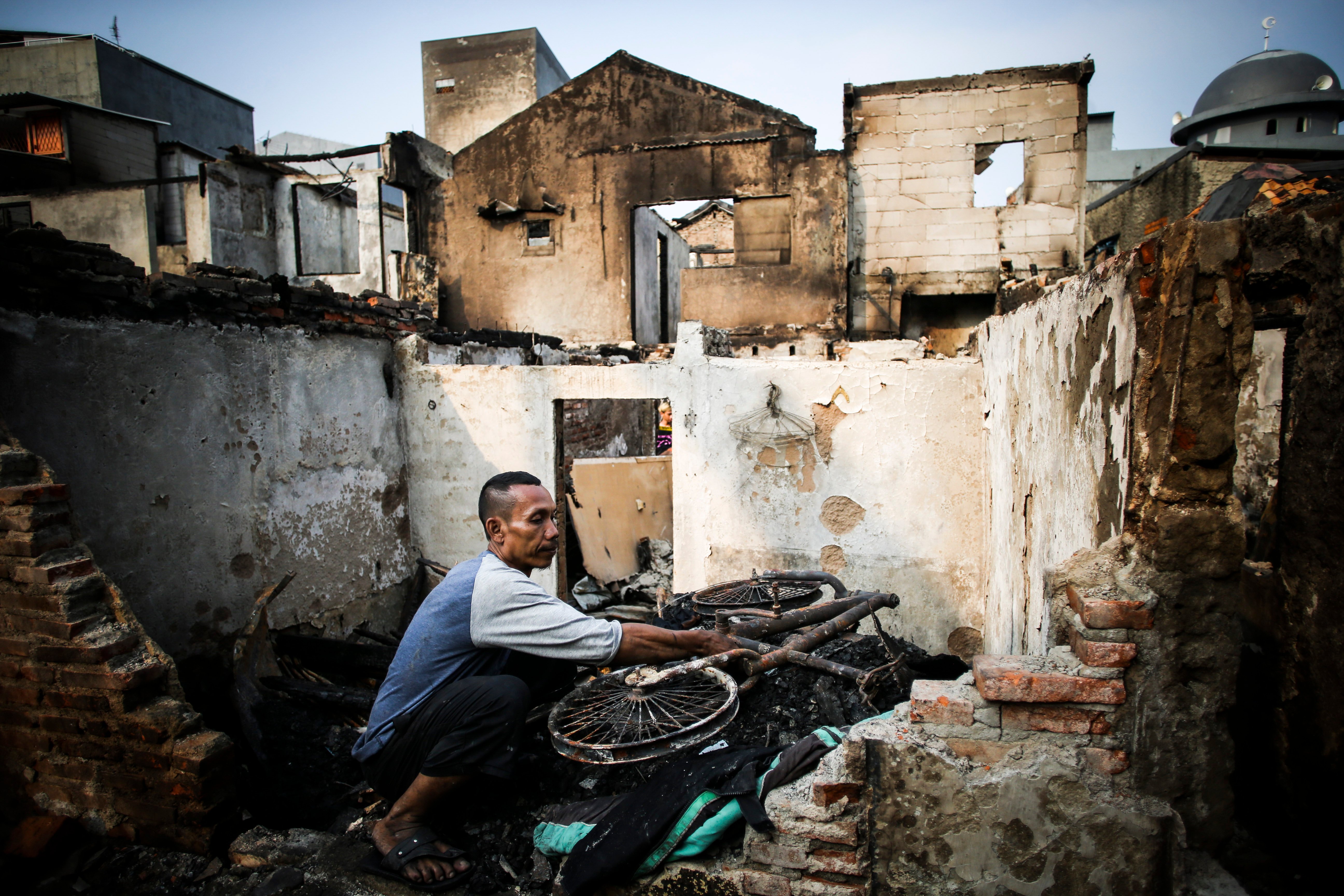 Seorang warga mencari barang berharga di dalam rumahnya yang terbakar di Tambora, Jakarta Barat, Selasa (26/7).