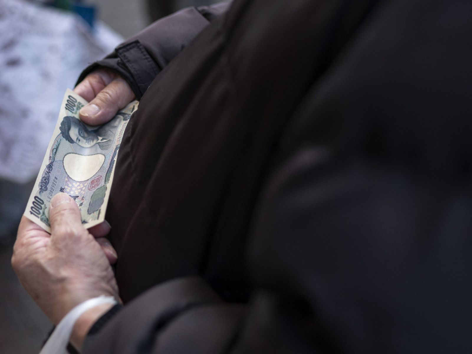 Seorang pria memegang uang 1.000 yen saat berbelanja di daerah Sunamachi Tokyo pada 9 Maret 2022. 