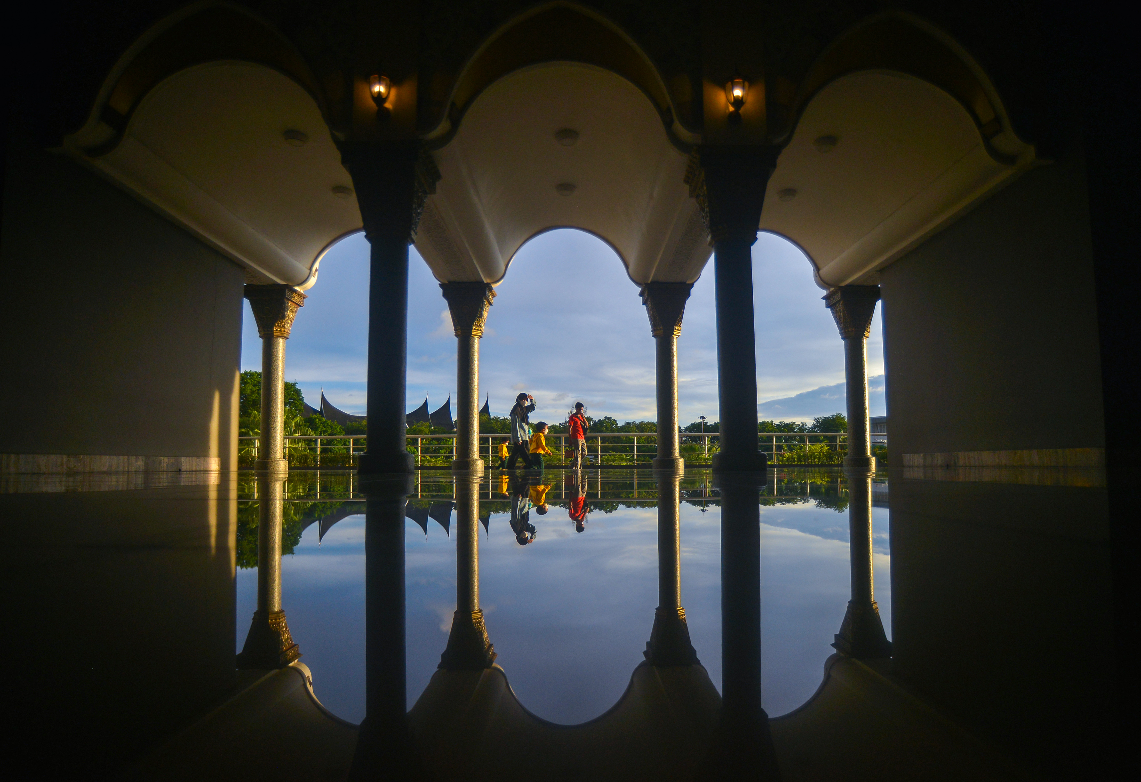Sejumlah pengunjung melintas di depan pintu angin Masjid Raya Sumatera Barat (Sumbar), di Padang, Rabu (13/4).
