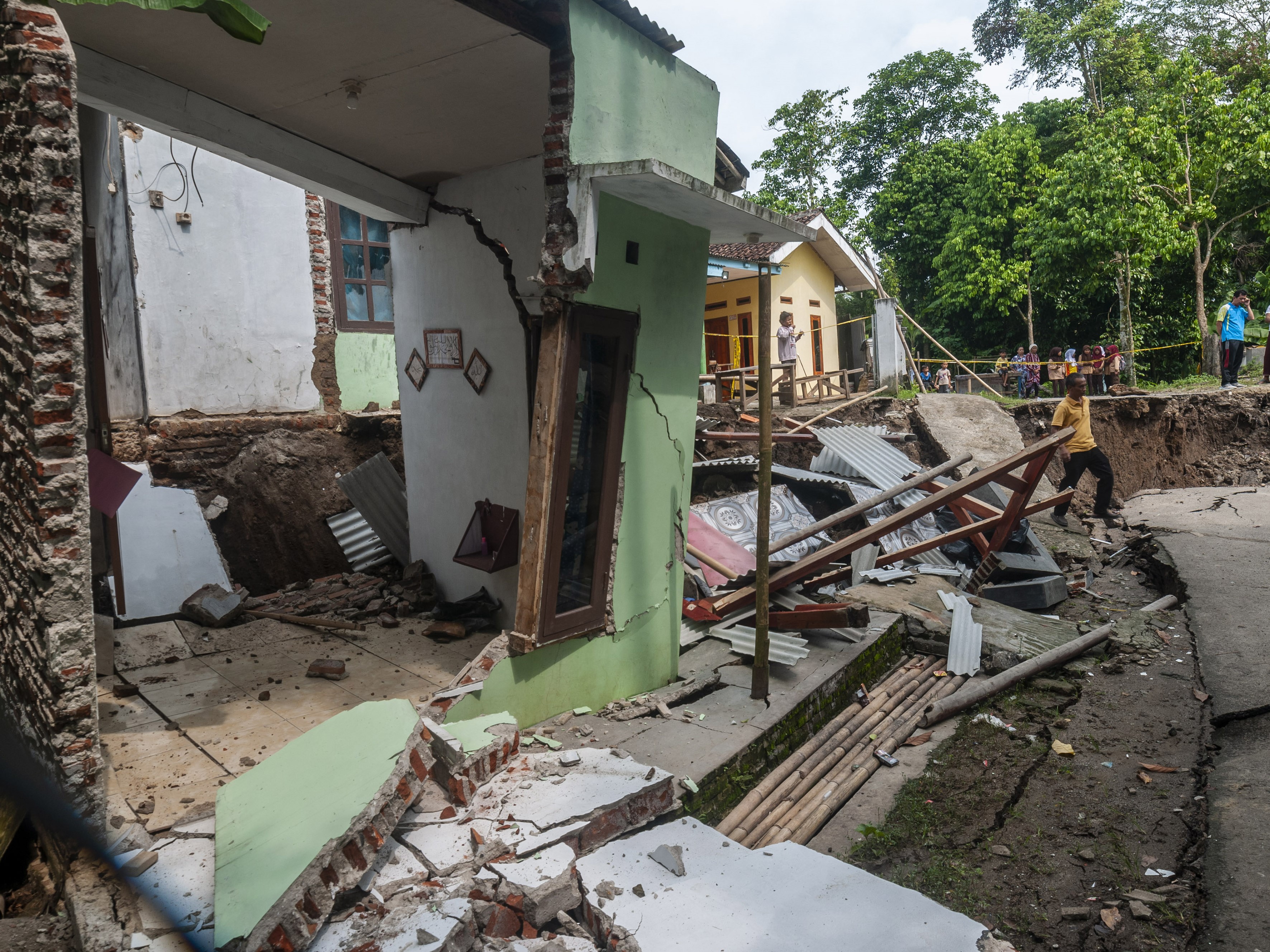 Warga berjalan melintasi rumah yang rusak akibat pergerakan tanah di Desa Cilangkap, Lebak, Banten, Sabtu (11/6/2022). 