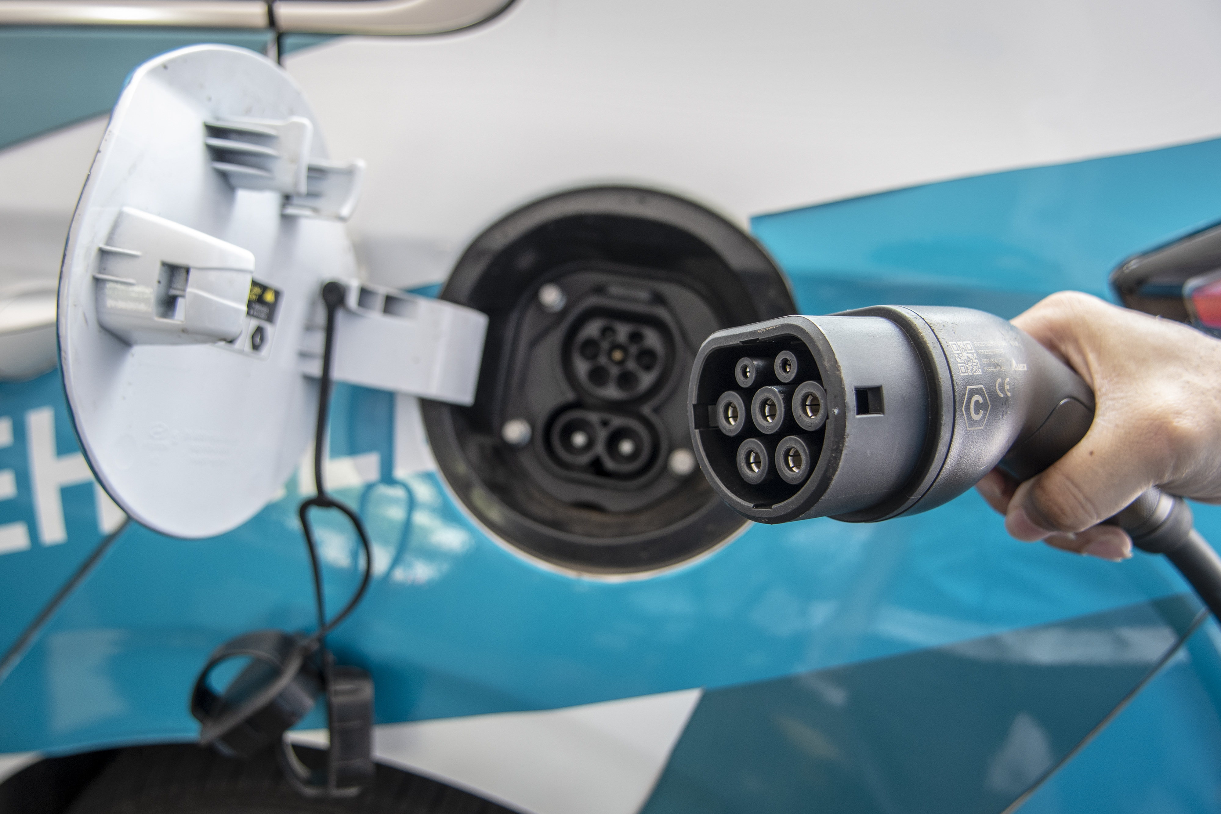 Petugas melakukan pengisian daya dari SPKLU ke kendaraan listrik.