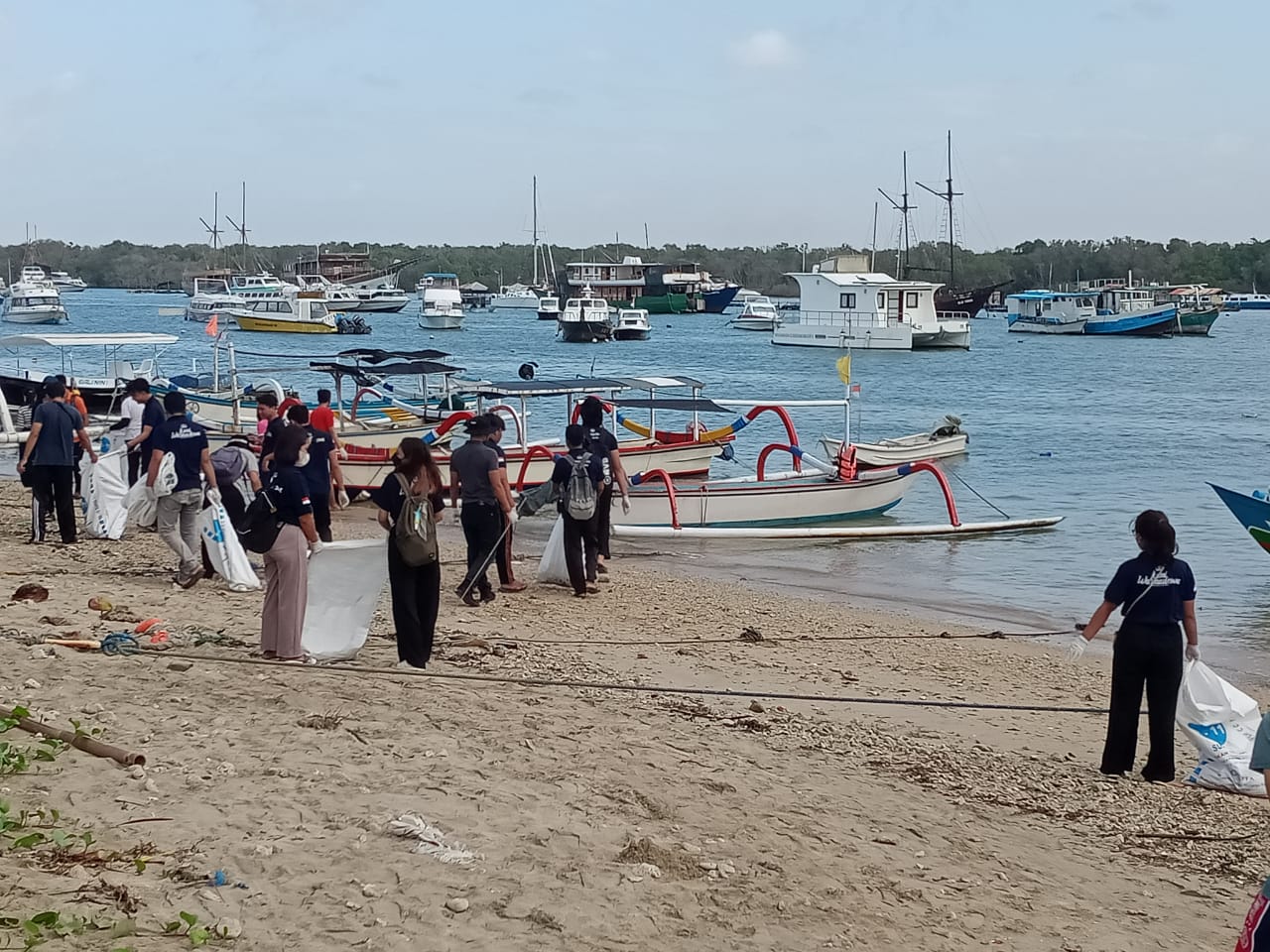 Mahasiswa melakukan pembersihan pantai dengan cara mengambil sampah plastik