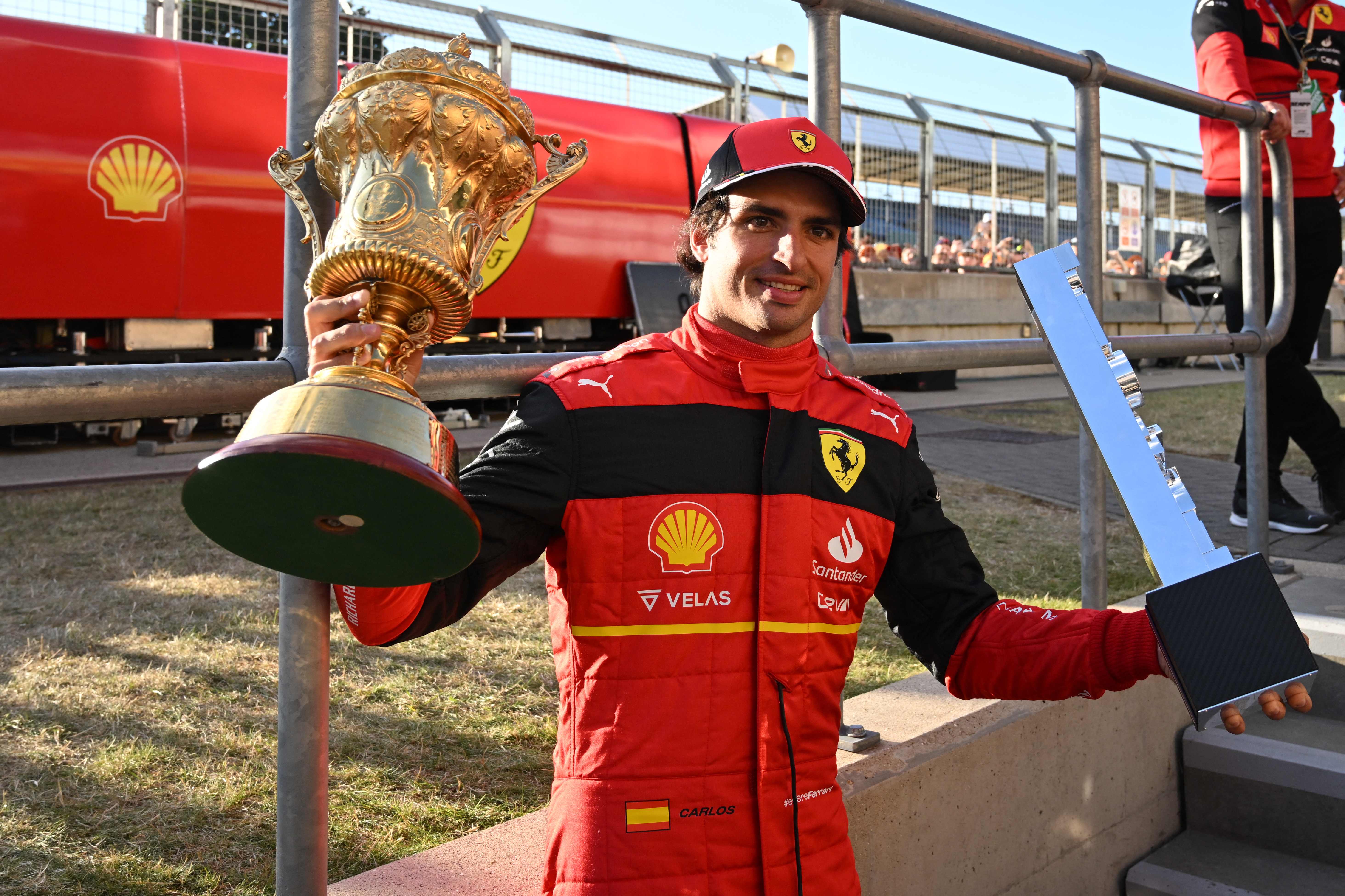 Pembalap Ferrari Carlos Sainz berpose dengan trofi juara usai menjadi yang tercepat di GP Inggris.