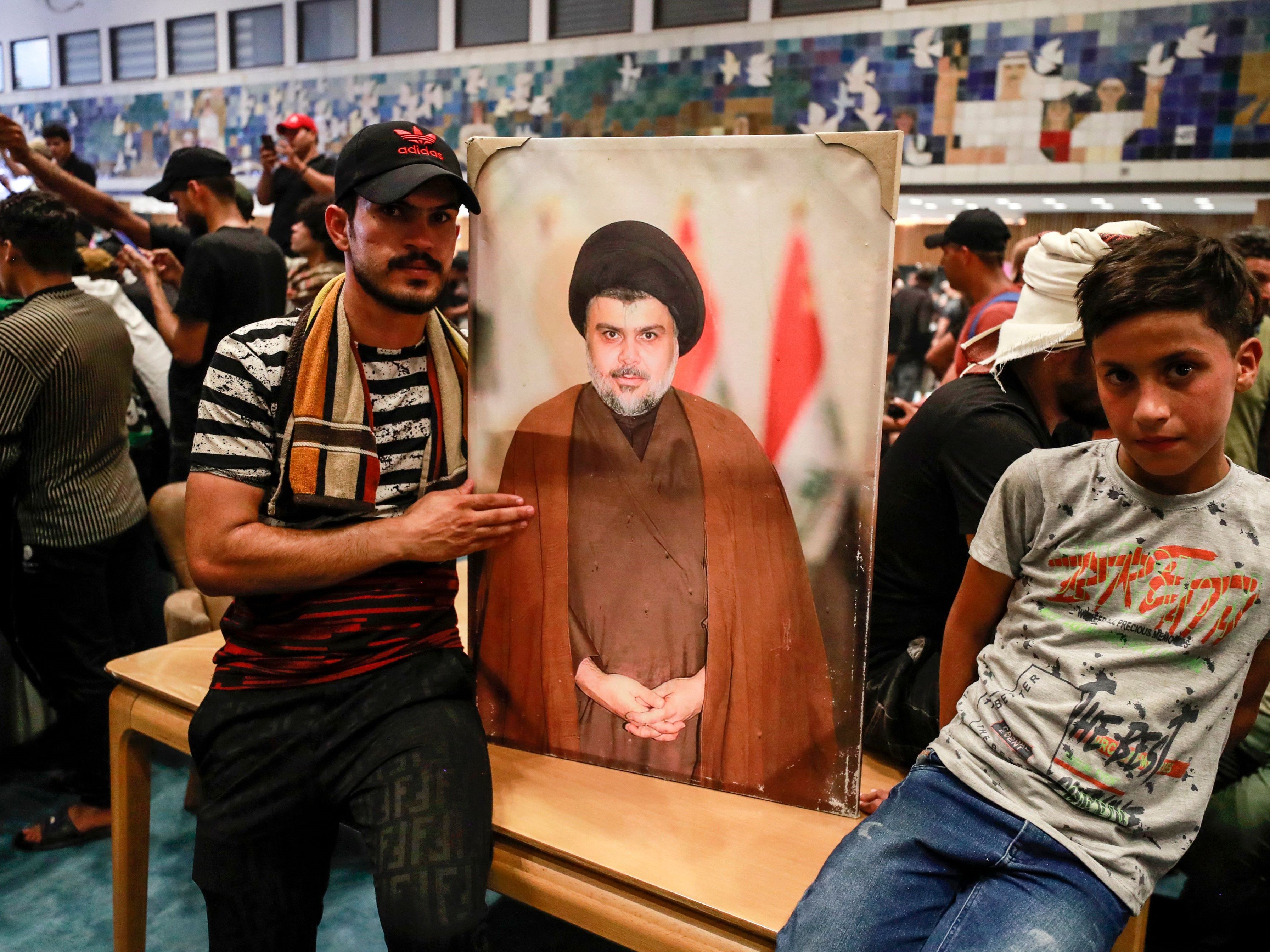 Pendukung ulama Irak Moqtada Sadr memegang foto pemimpin mereka di dalam parlemen, Zona Hijau, keamanan tinggi ibu kota Baghdad.