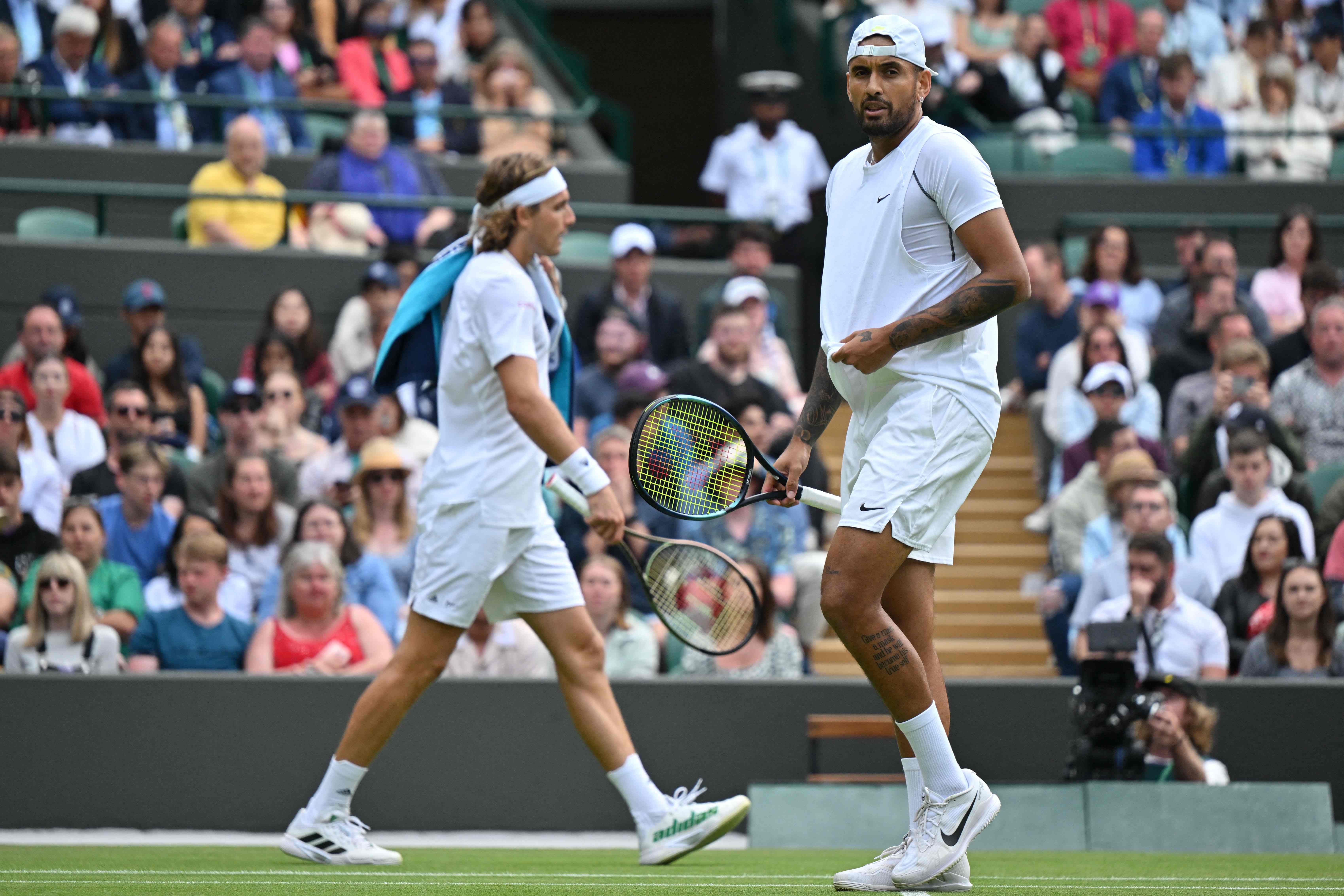 Petenis Yunani Stefanos Tsistipas (kiri) dan petenis Australia Nick Kyrgios saling melintas saat berhadapan di Wimbledon.