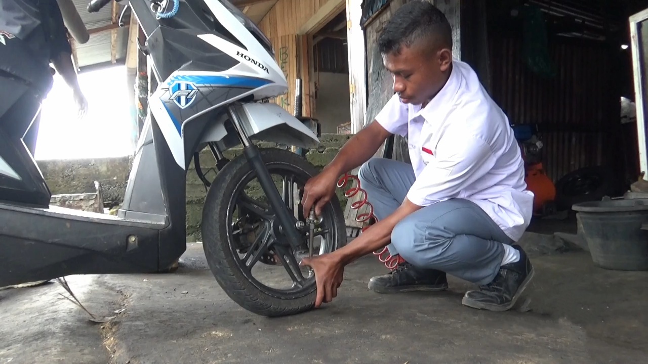 Asis memperbaiki motor pelanggannya
