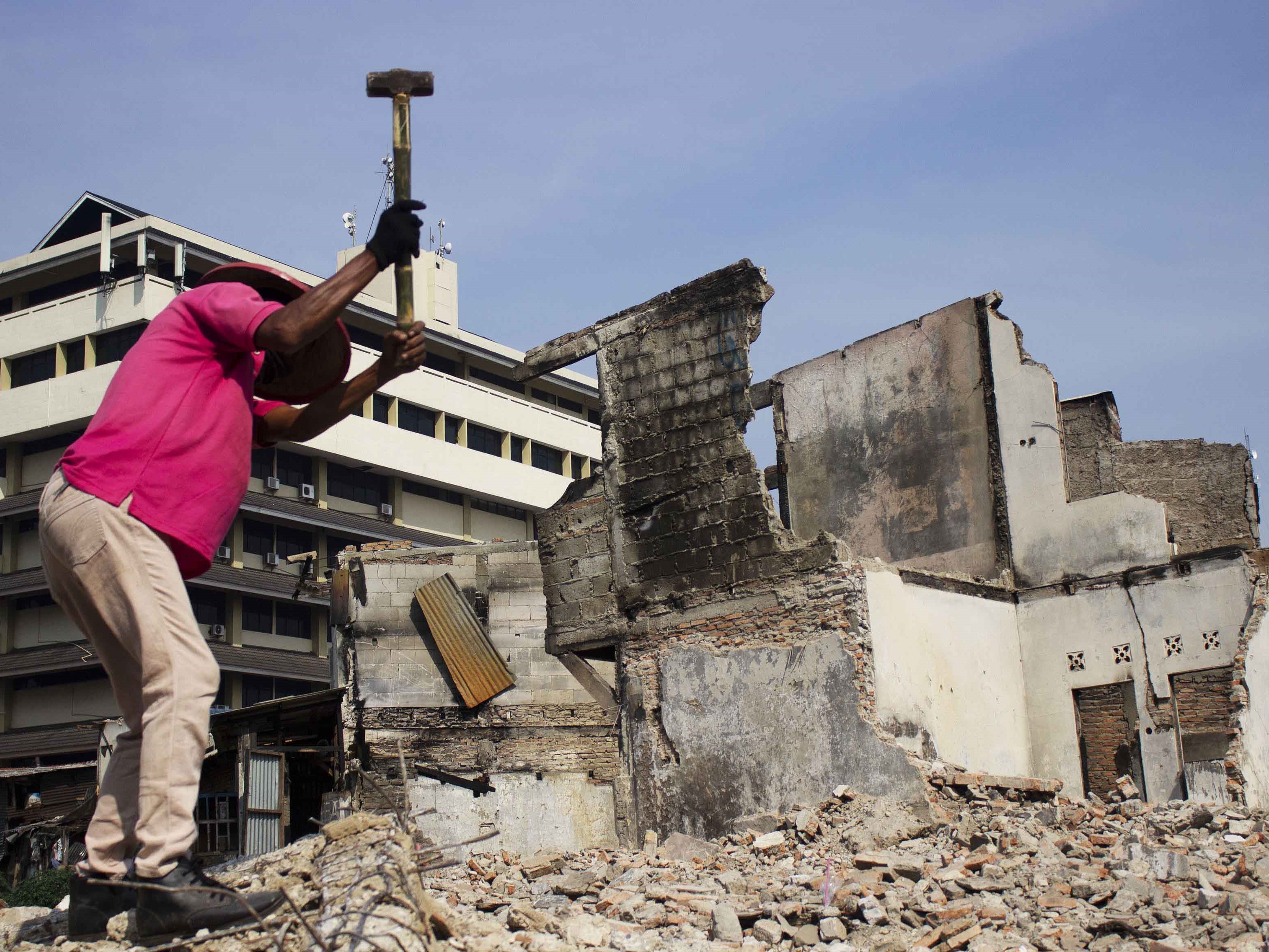 Warga menghancurkan sisa bangunan di lokasi bekas kebakaran Pasar Gembrong di Cipinang Besar Utara, Jakarta, Jumat (1/7).