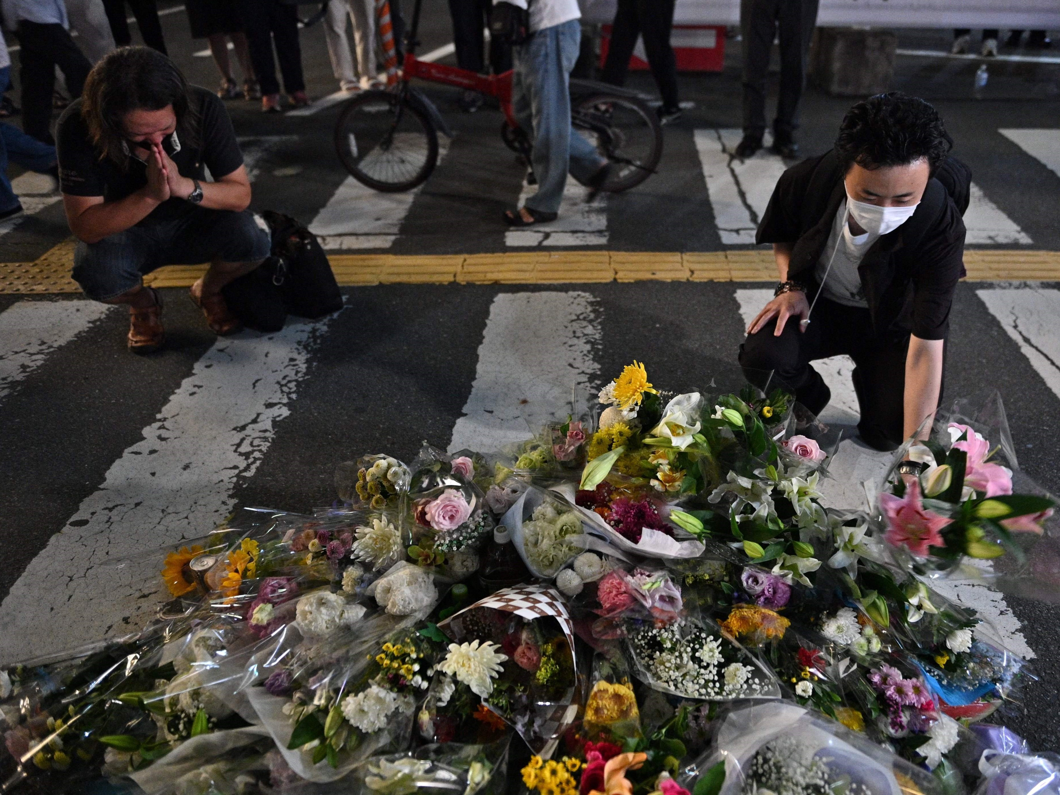 Orang-orang berdoa dan meletakkan bunga di tempat kejadian di luar Stasiun Yamato-Saidaiji di Nara.