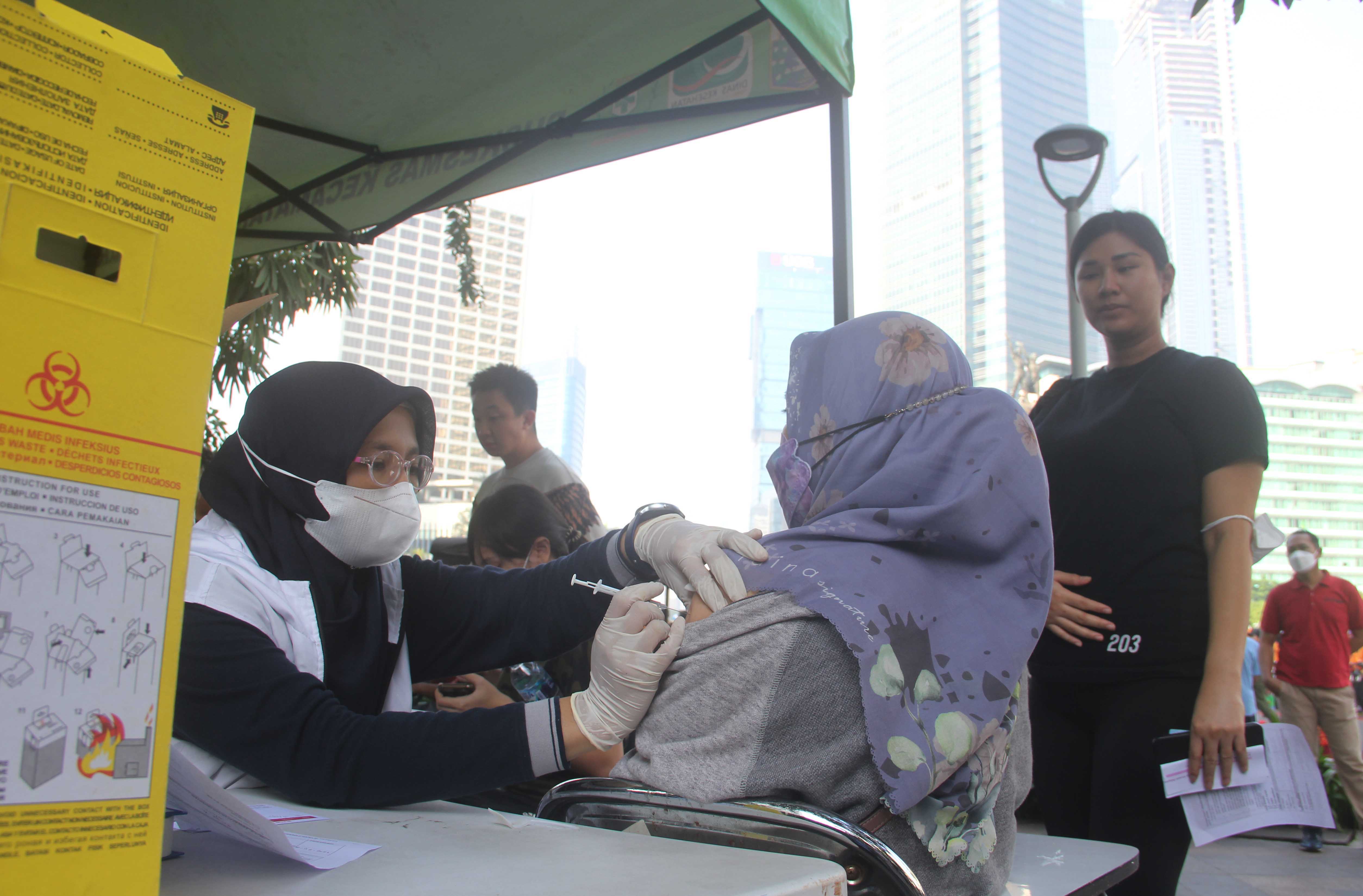 Nakes menyuntikan vaksin covid-19 dosis booster kepada warga yang tengah ambil bagian di HBKB atau car free day di Bundaran HI, Jakarta.