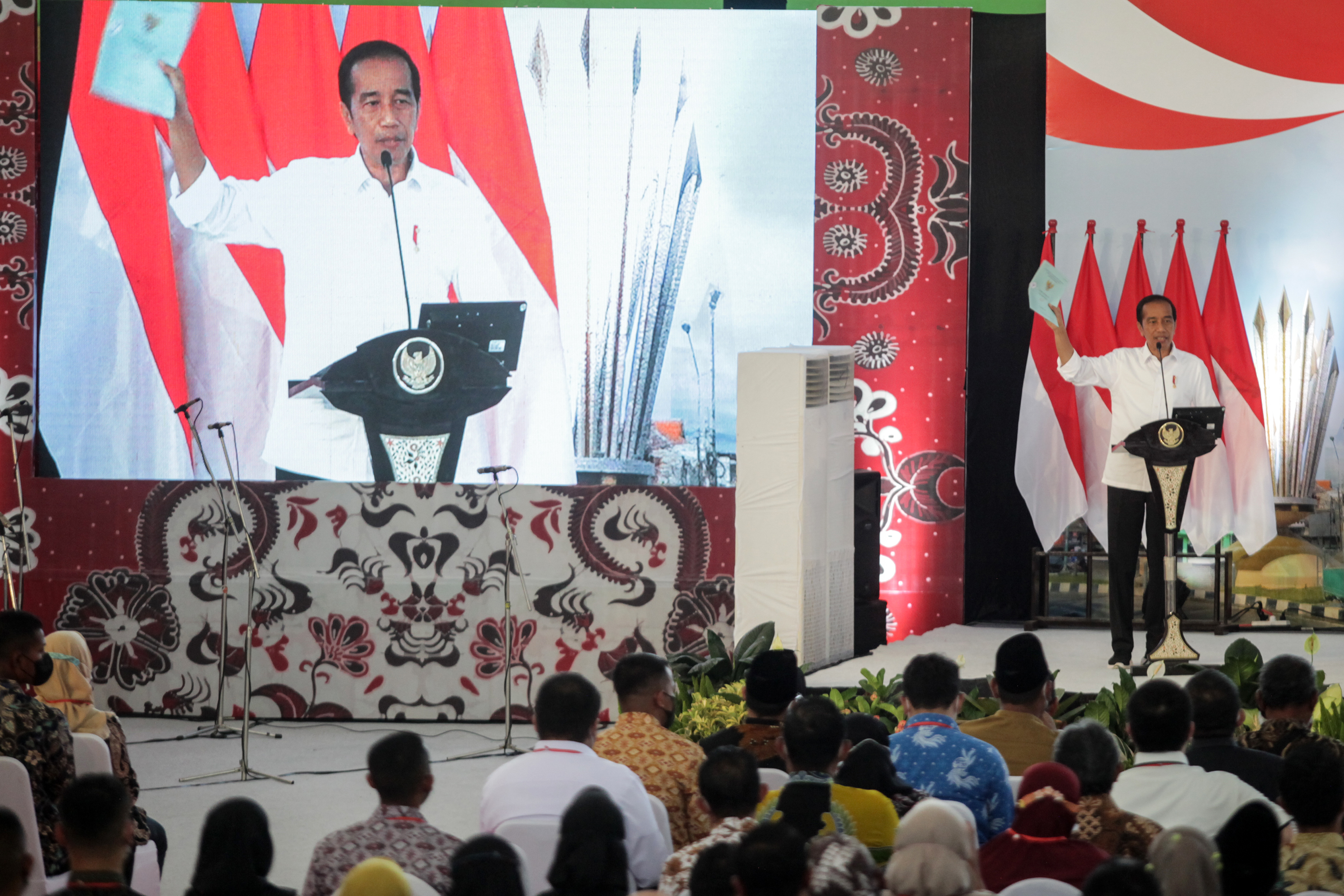 Presiden Jokowi mengangkat sertifikat tanah warga di Gelora Delta Sidoarjo, Jawa Timur.