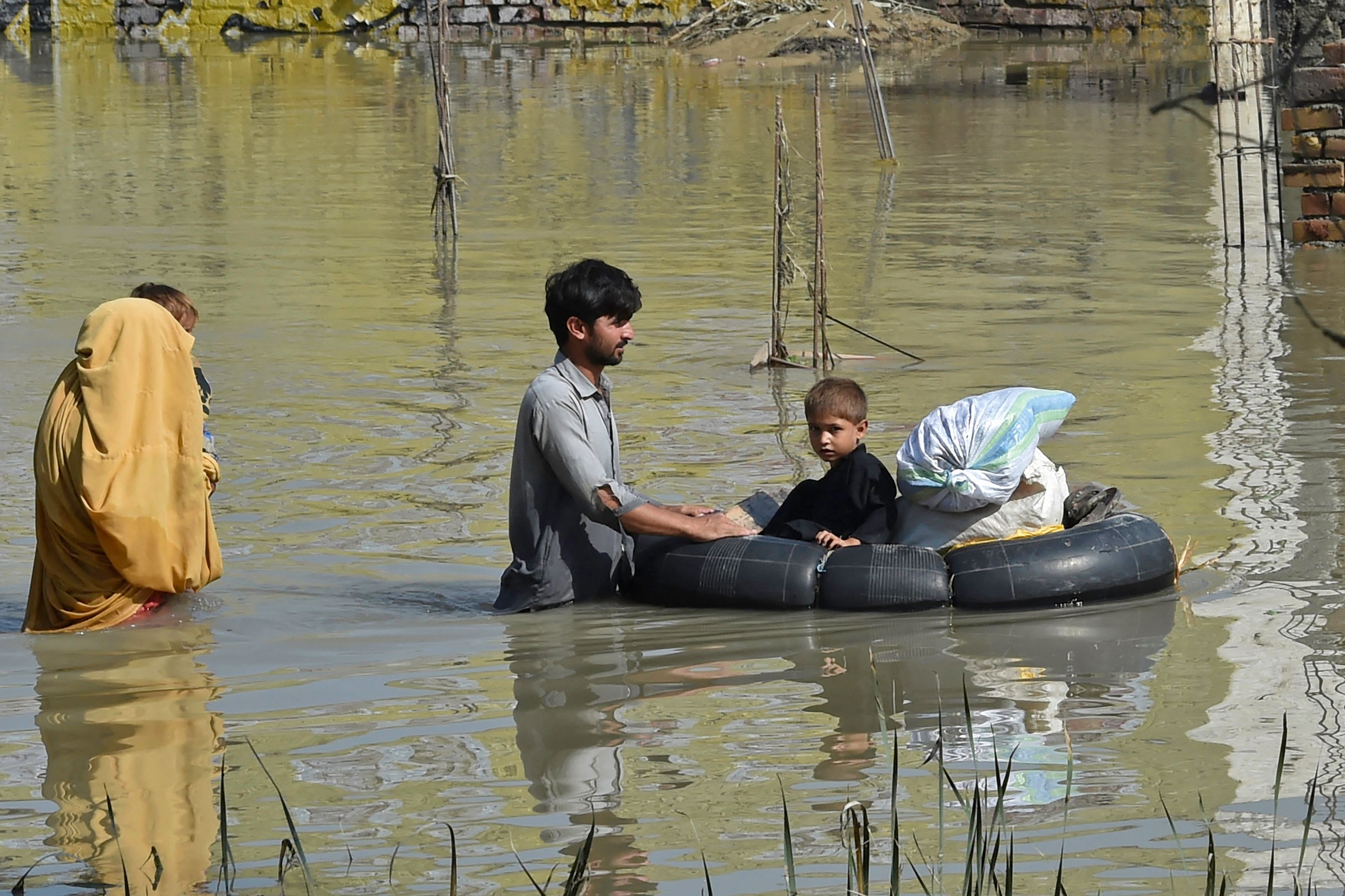 Satu keluarga korban banjir bandang di Charsadda, Distrik Khyber Pakhtunkhwa, Pakistan, mengungsi ke tempat aman, Senin (29/8).